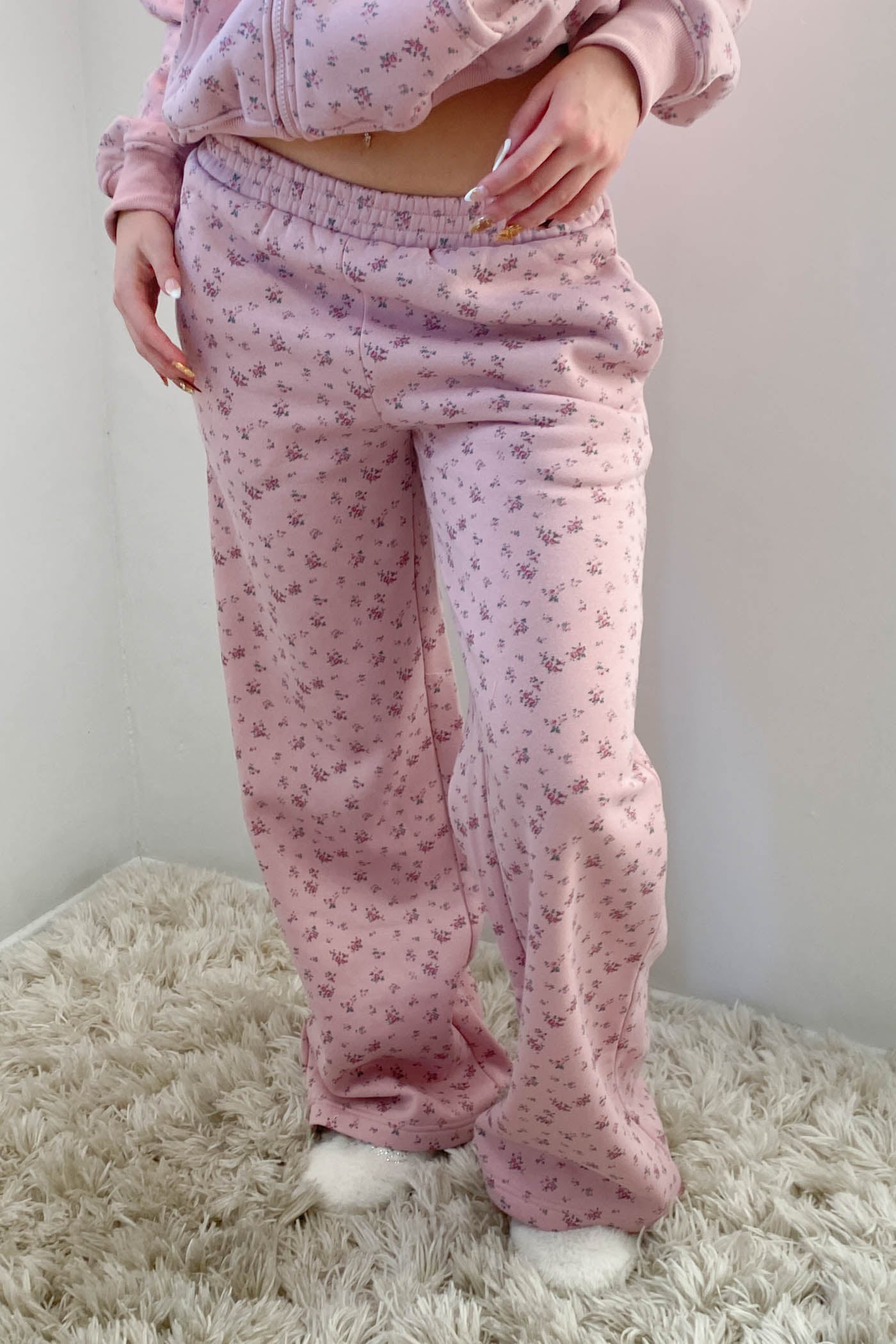 Person wearing pink pajama set with floral pattern on a white background