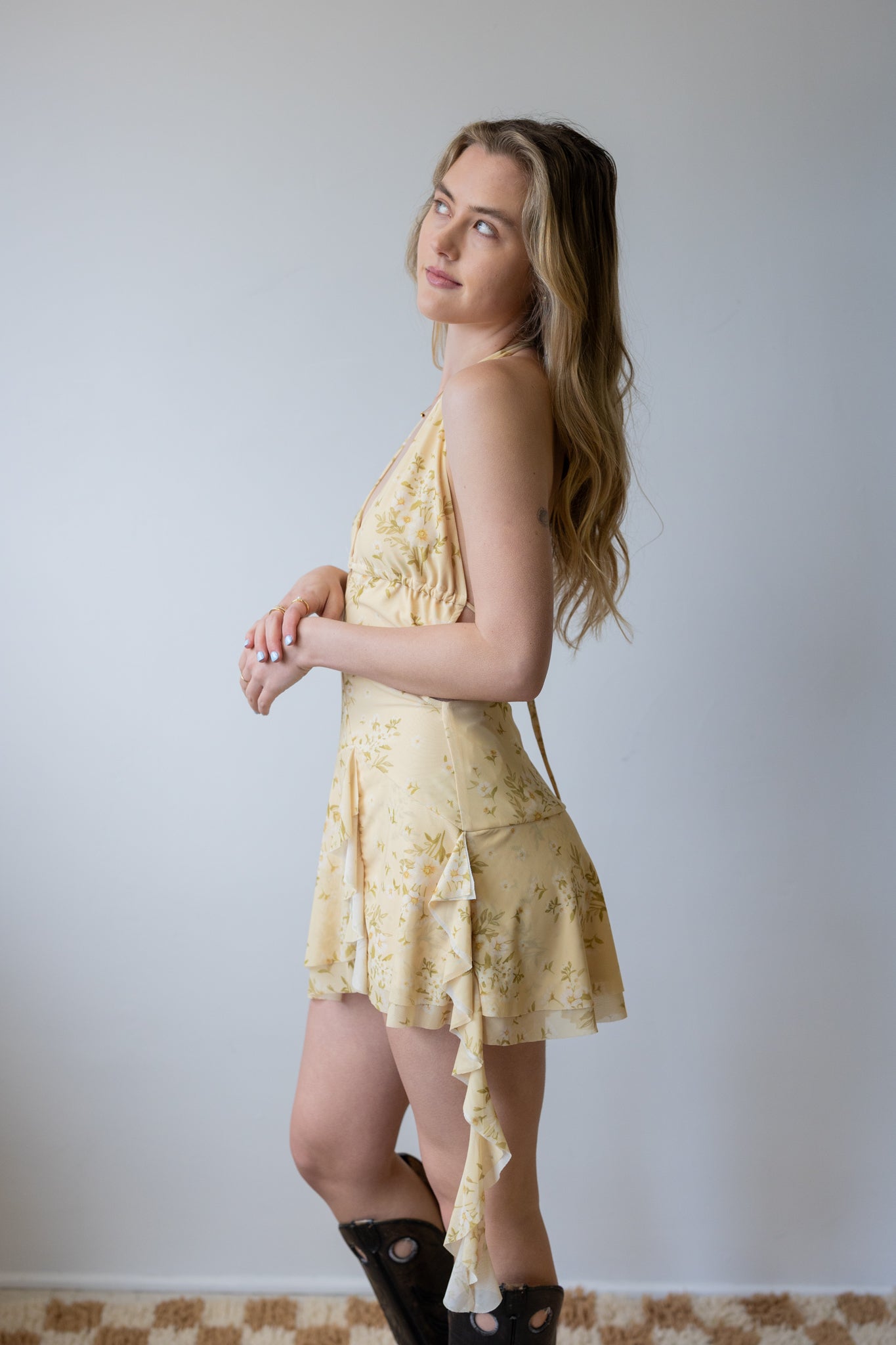 Woman wearing a yellow lace dress against a plain background