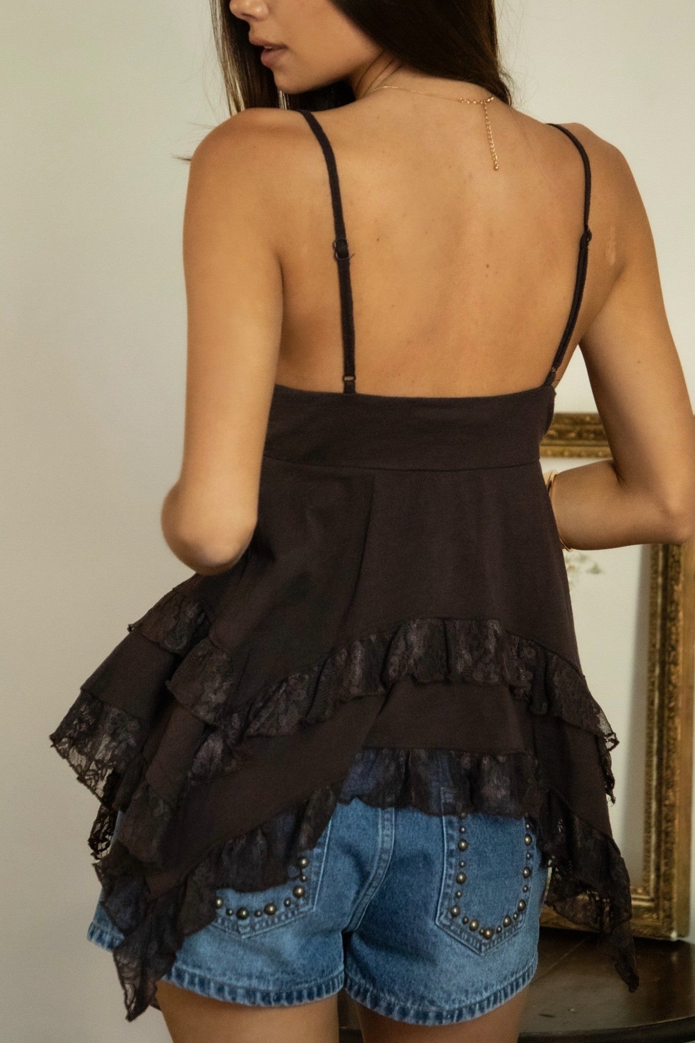 Woman wearing a black layered top and denim shorts with a blurred background