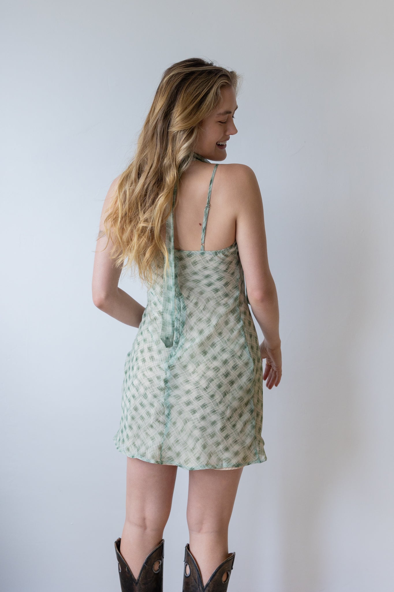 Woman wearing a green patterned dress against a plain background