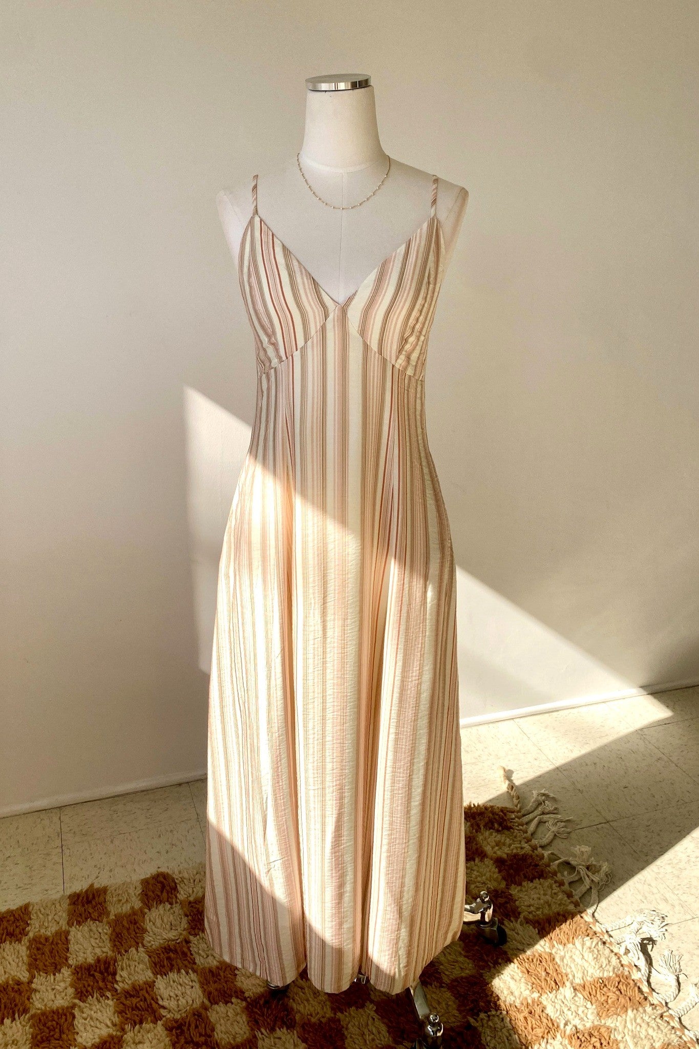 Striped dress on a mannequin against a plain wall.