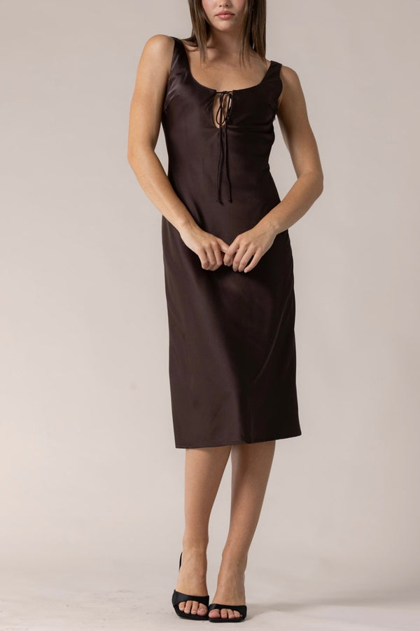 Woman wearing a brown slip dress against a plain background