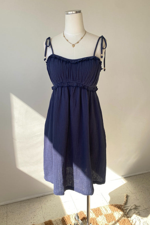Navy blue dress on a mannequin against a white wall