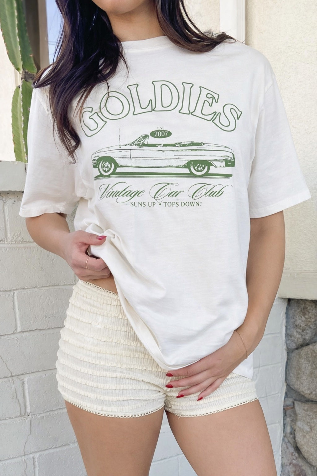 Person wearing a white t-shirt with 'Goldies Vintage Car Club' graphic design.