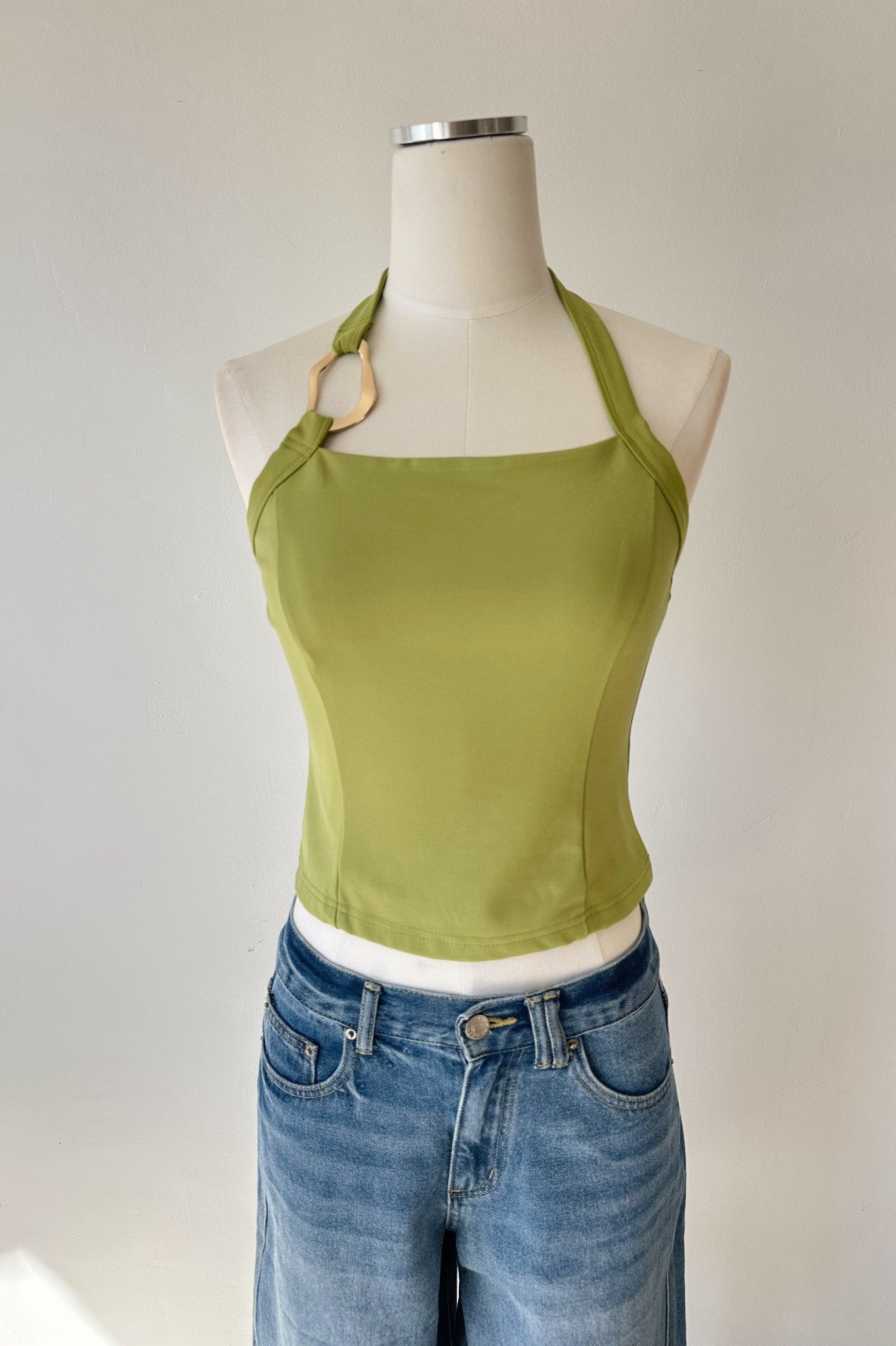 Green tank top on a mannequin with a white background