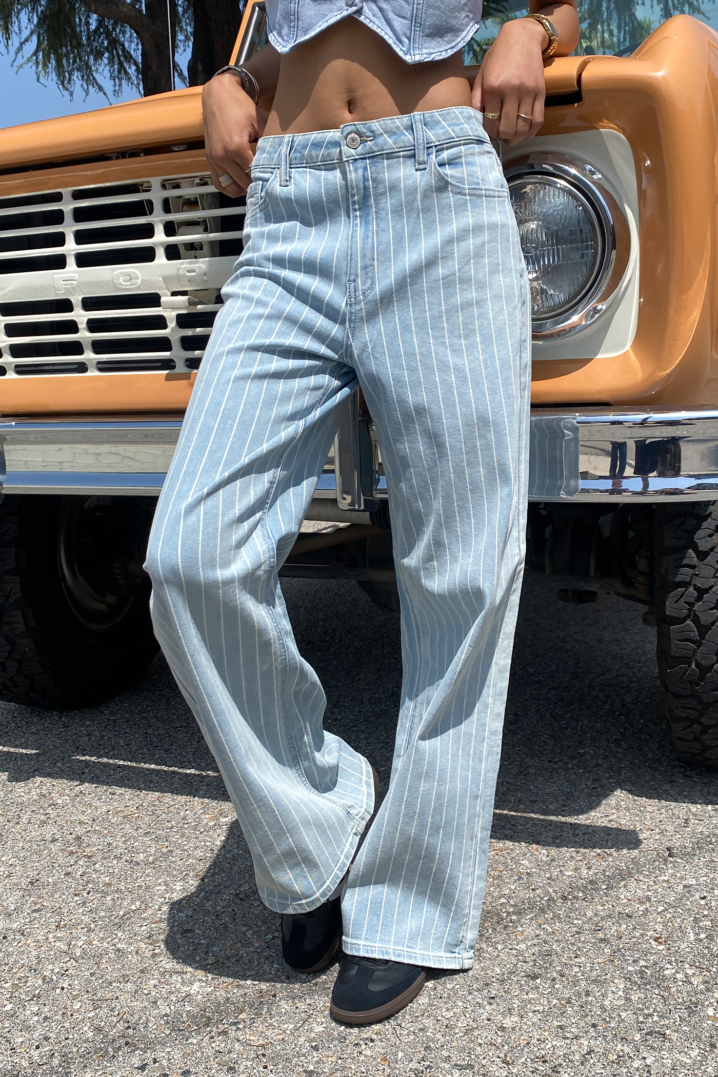 Person wearing light blue striped jeans standing in front of a vintage truck.