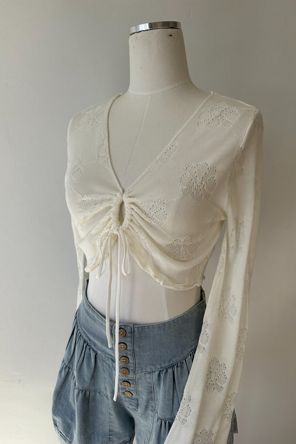 Mannequin wearing a cream-colored embroidered top and blue denim skirt against a plain background