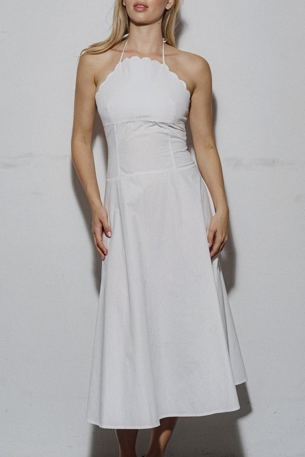 Woman wearing a white halter neck dress against a plain background