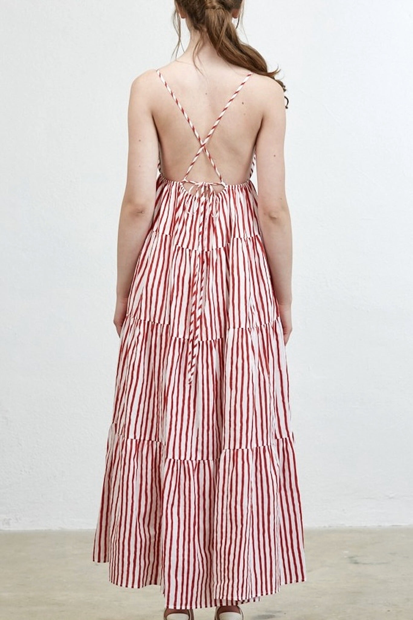 Red and white striped dress with open back worn by a person on a plain background