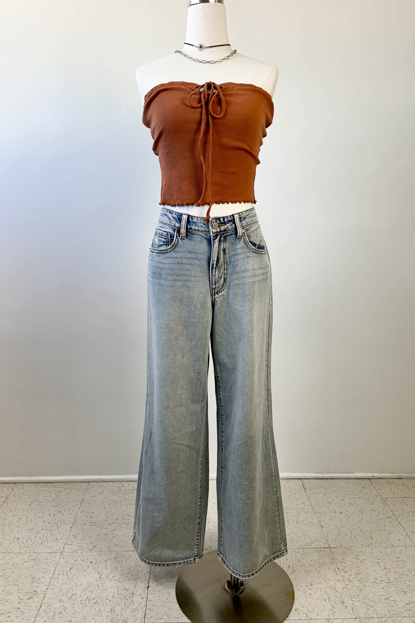 Mannequin wearing a brown top and light blue jeans against a white background