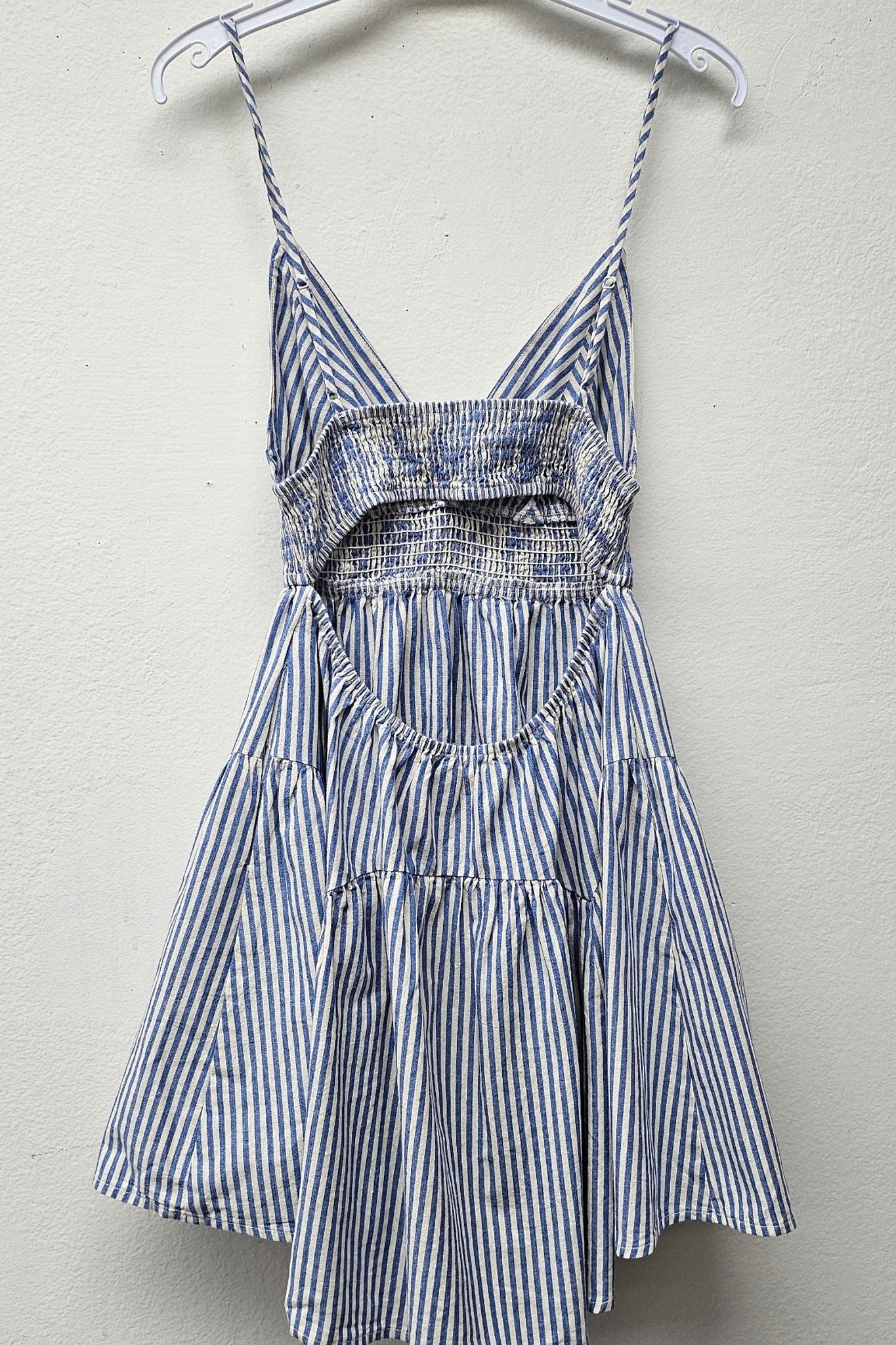 Striped dress hanging on a hanger against a plain background