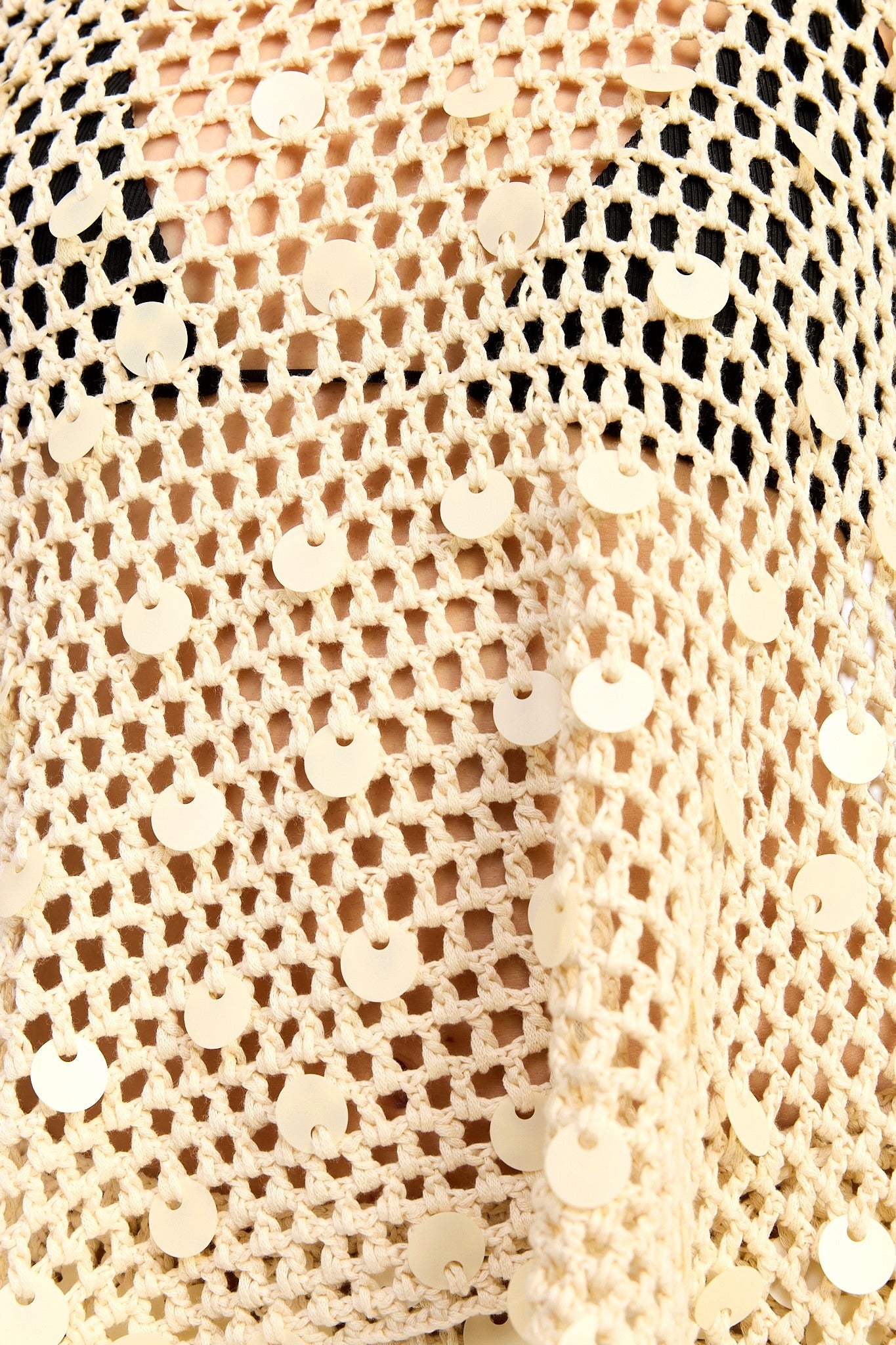 Close-up of beige sequin fabric with a textured pattern