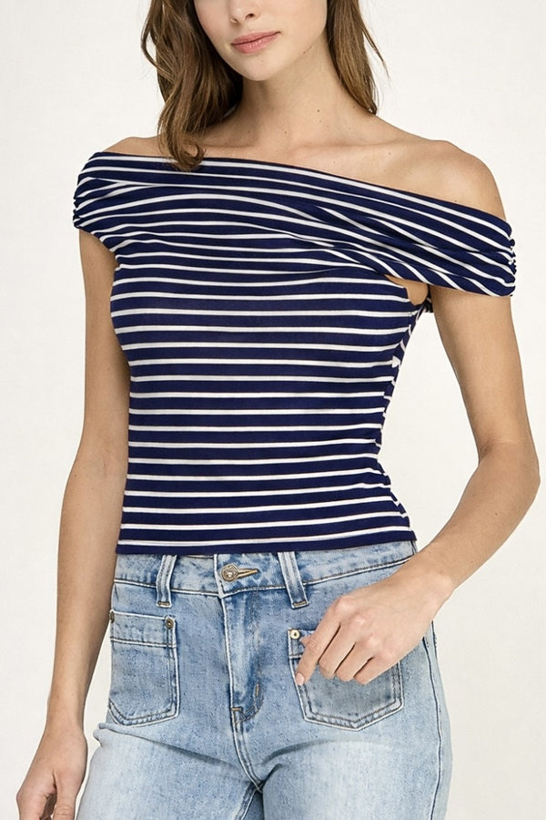 Woman wearing a navy and white striped off-shoulder top with light blue jeans on a plain background