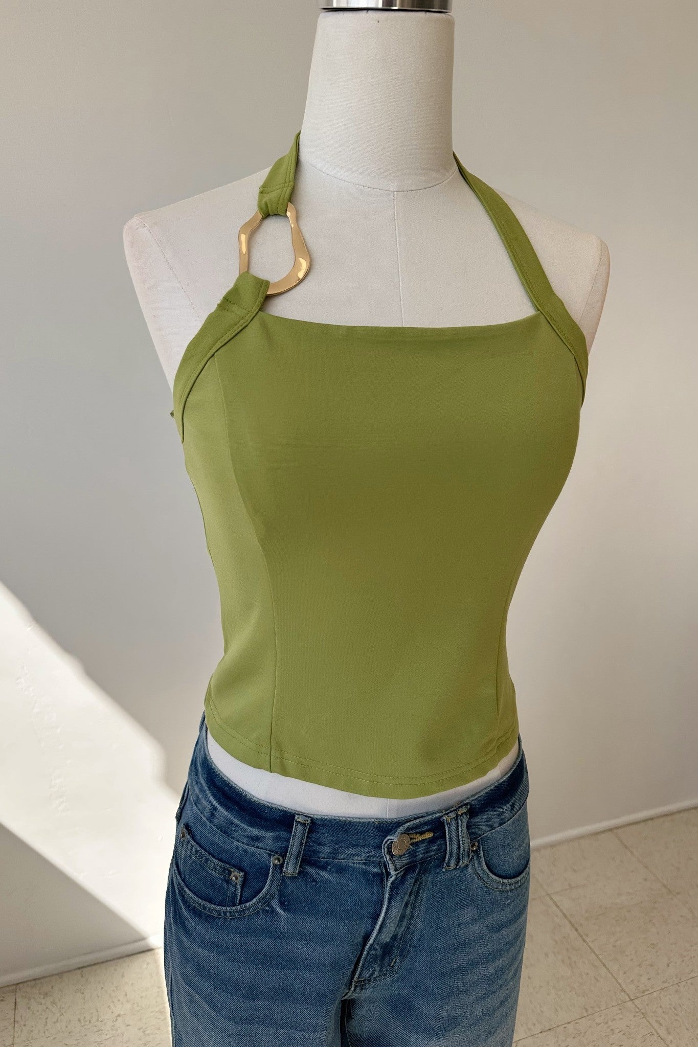 Green tank top on a mannequin with a white background