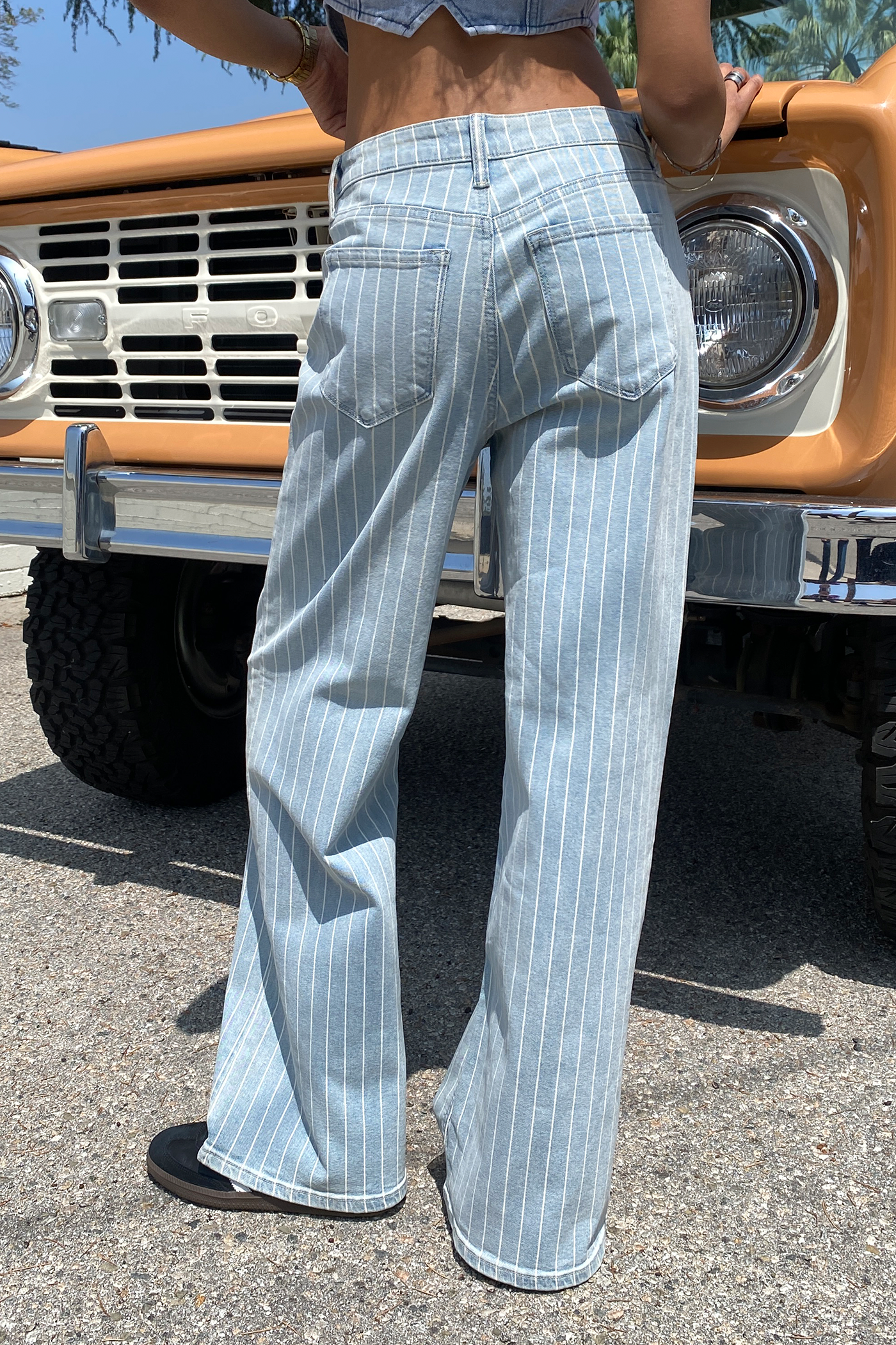 Person wearing light blue pinstripe pants standing in front of a vintage truck.