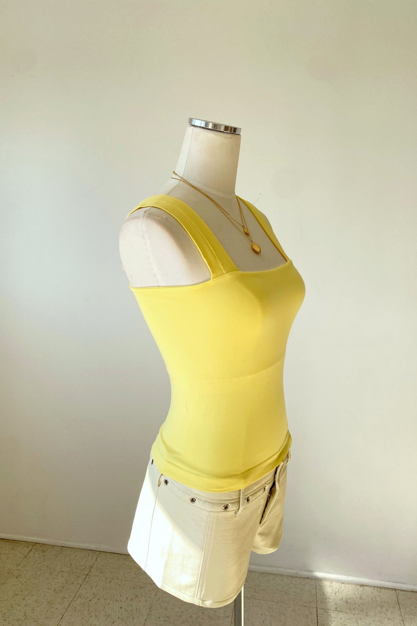 Yellow tank top on a mannequin against a plain background
