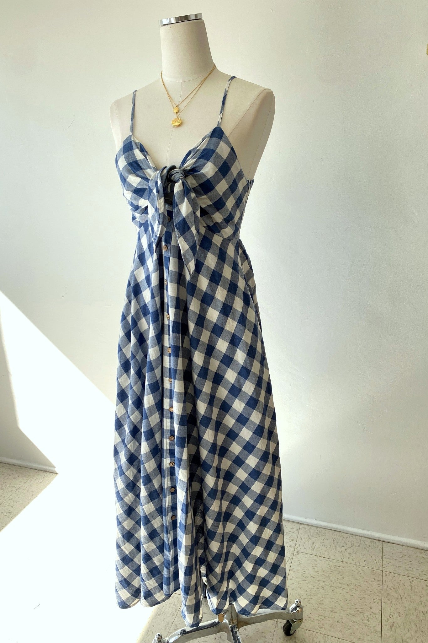 Blue and white checkered dress on a mannequin against a plain background