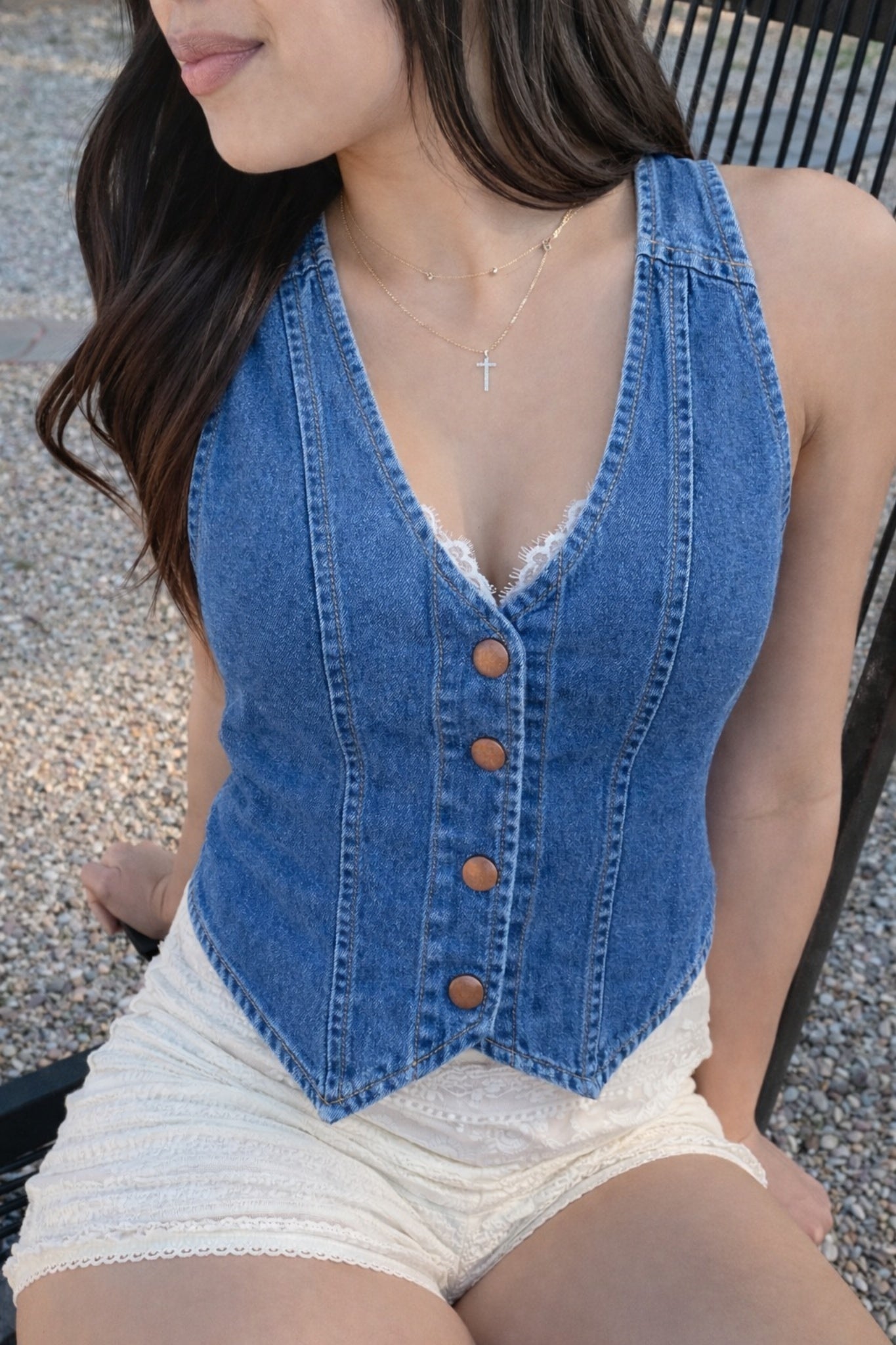 Woman wearing a denim corset over a white lace top and shorts.