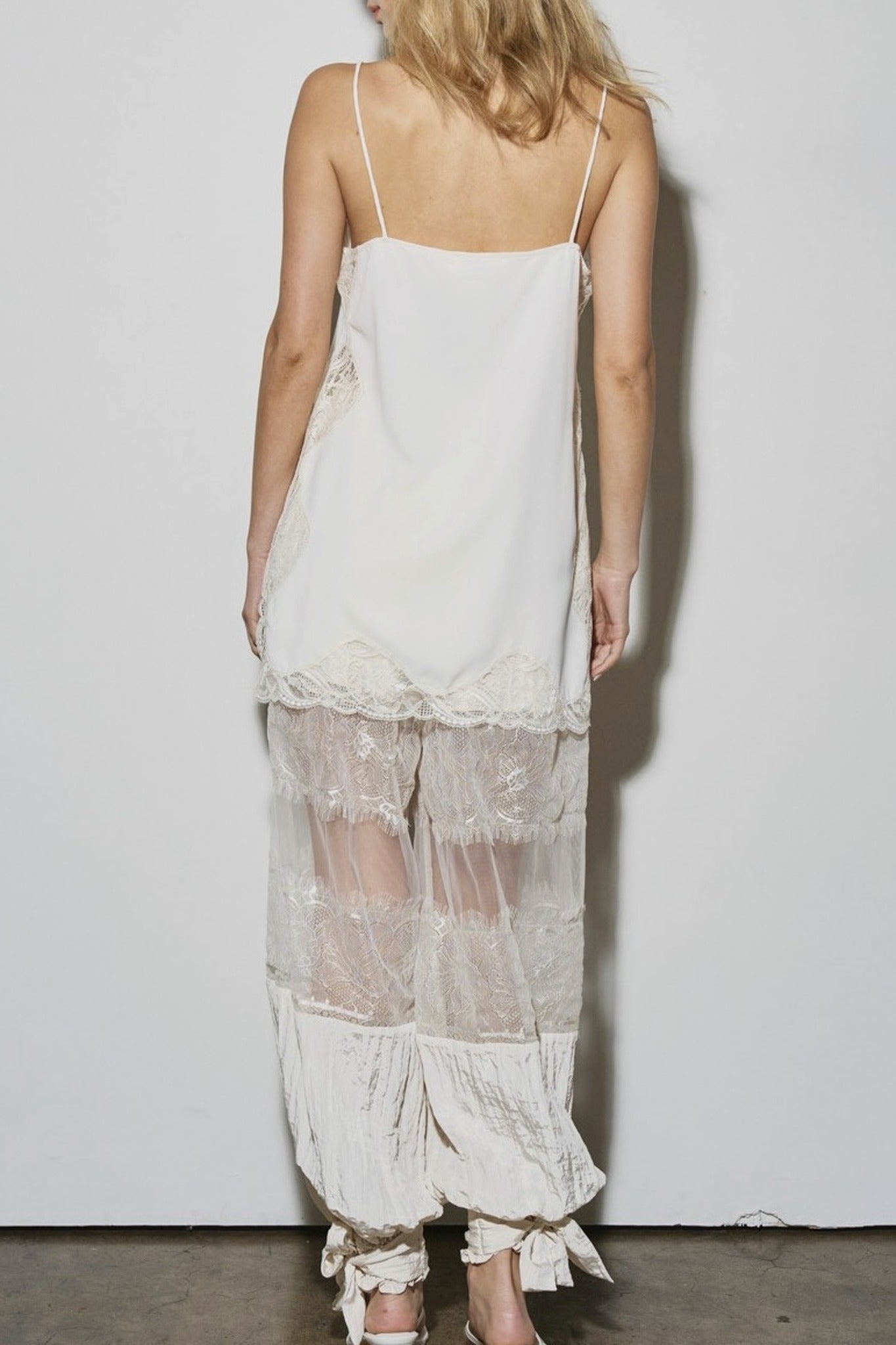 Woman wearing a white lace dress against a plain background
