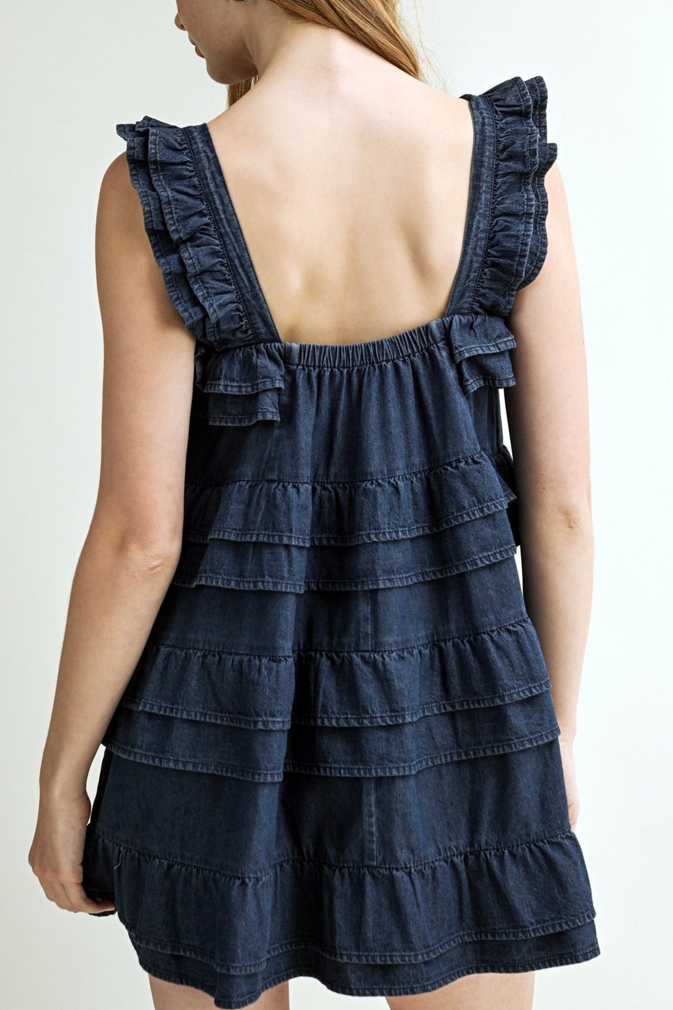 Navy blue tiered dress with ruffled straps on a plain background