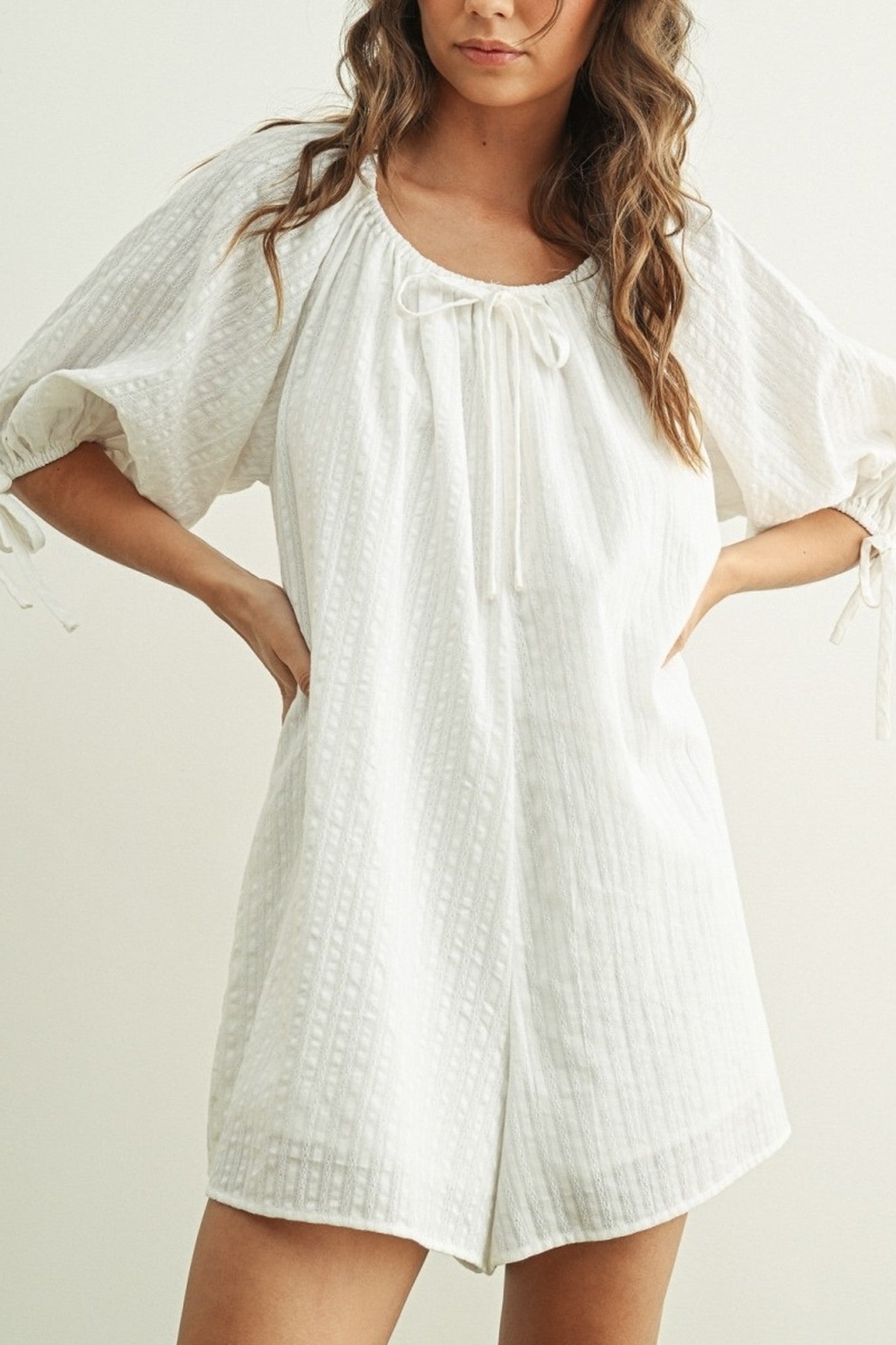 Woman wearing a white dress with short sleeves on a plain background