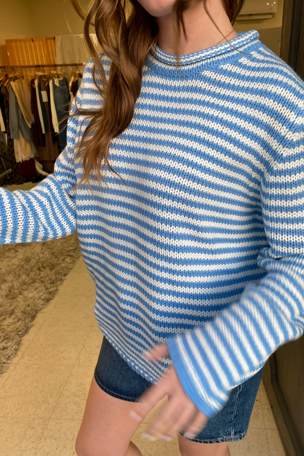 Person wearing a blue and white striped sweater in a clothing store.