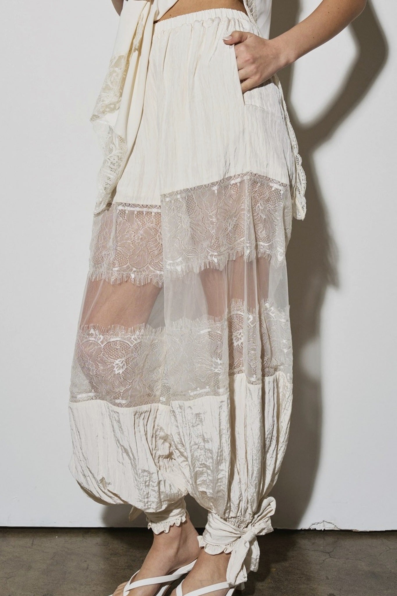 White lace pants worn by a person on a plain background