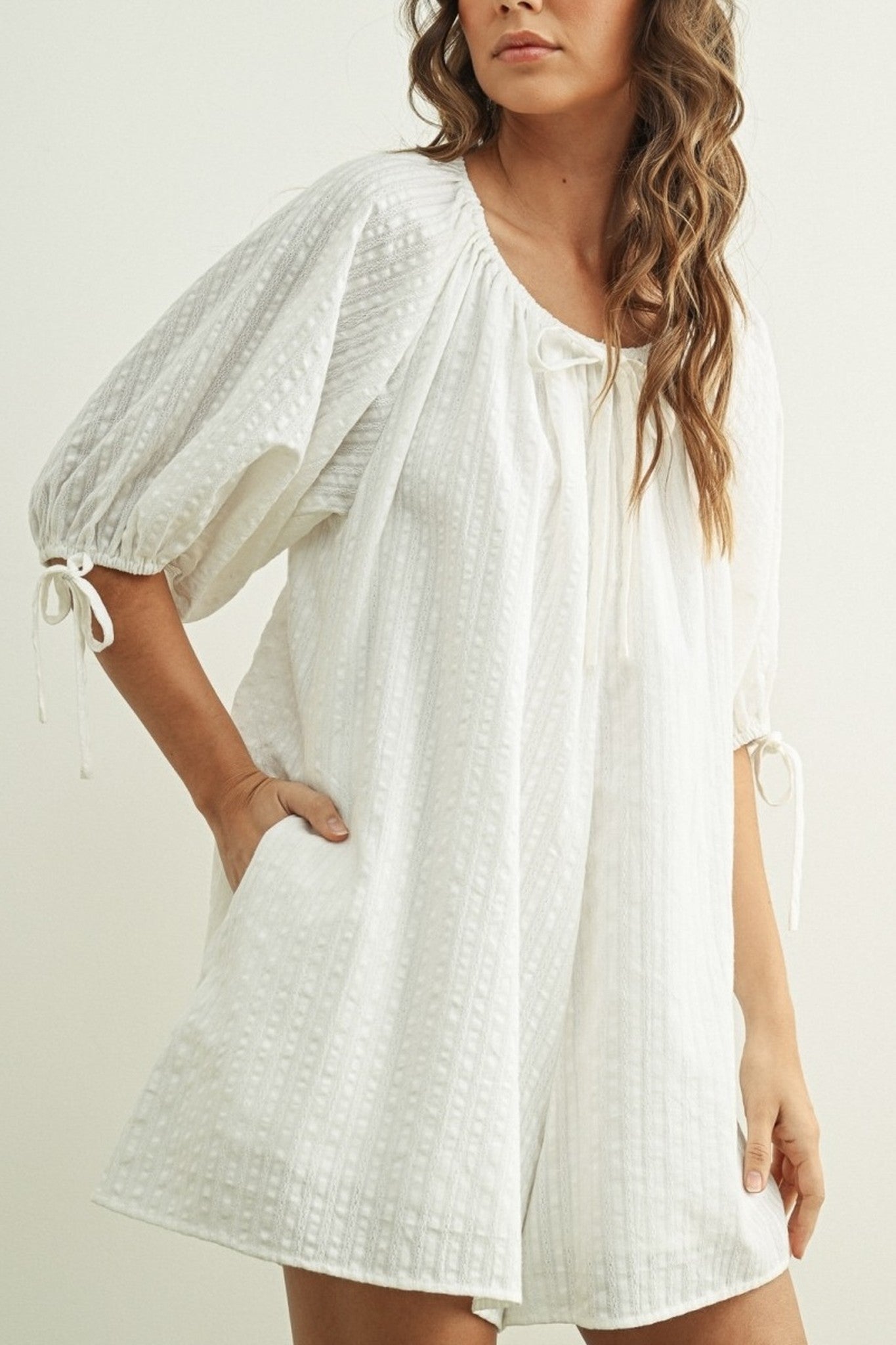 Woman wearing a white dress with puff sleeves against a plain background