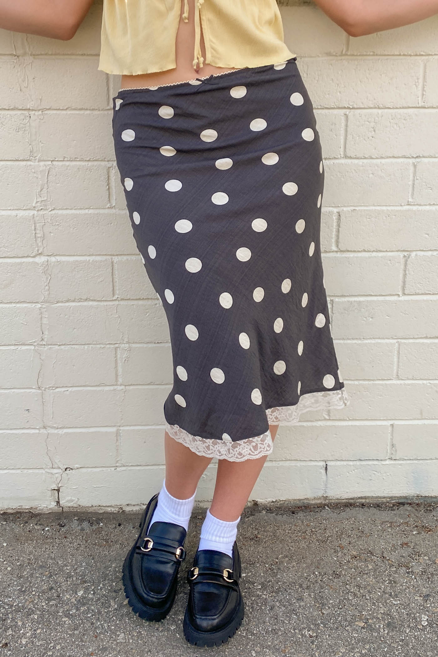 Person wearing a polka dot skirt with a plain background