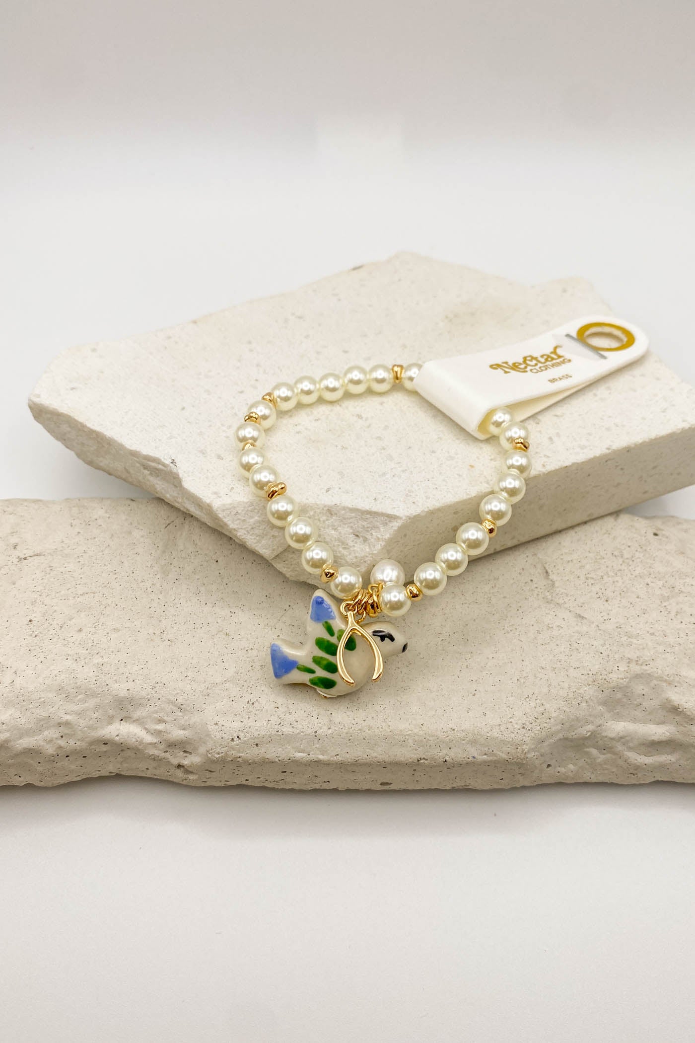 Pearl bracelet with a turtle charm on a stone surface