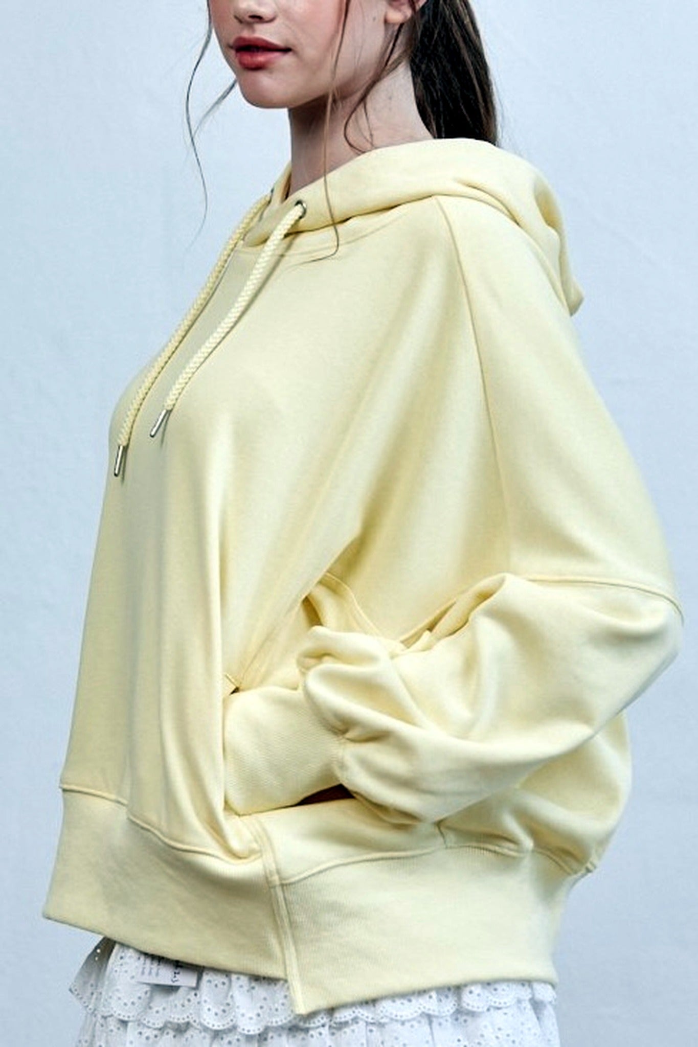 Person wearing a light yellow hoodie against a plain background
