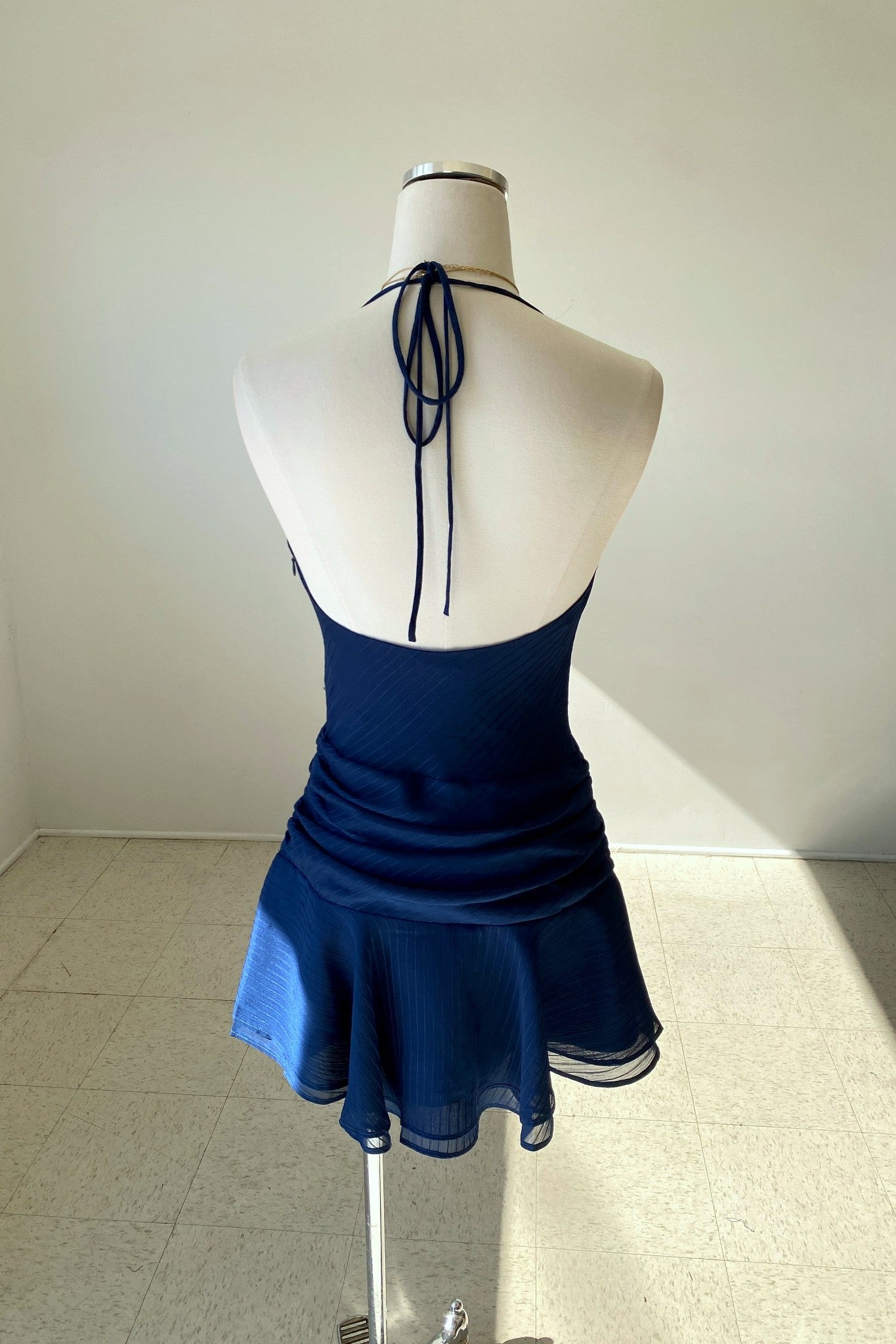 Navy blue dress on a mannequin against a white wall