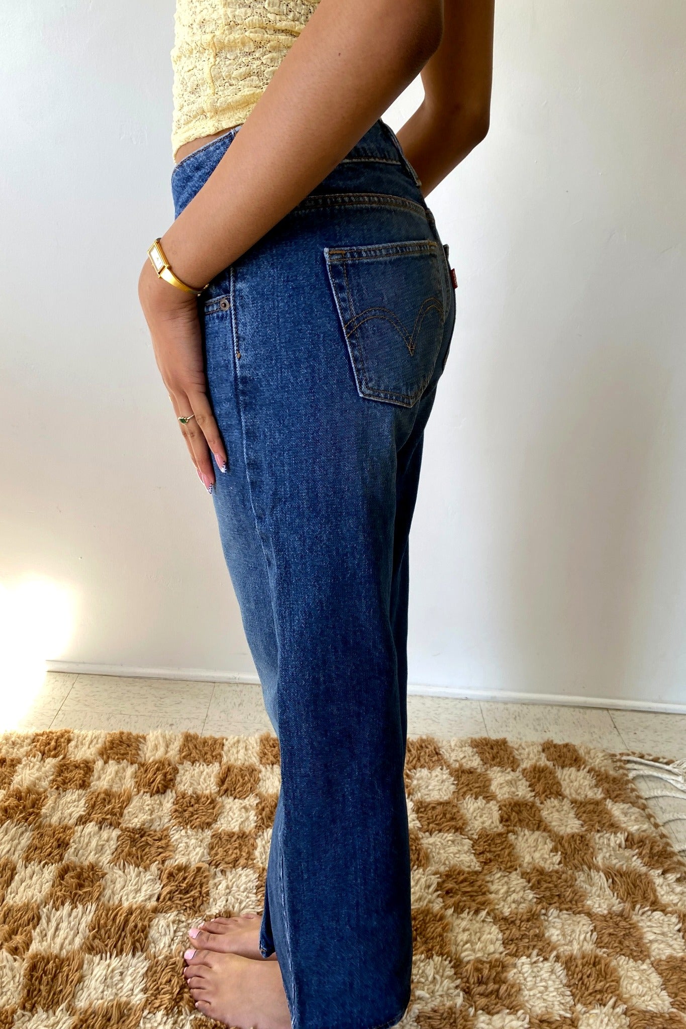 Person wearing blue jeans standing on a checkered floor.