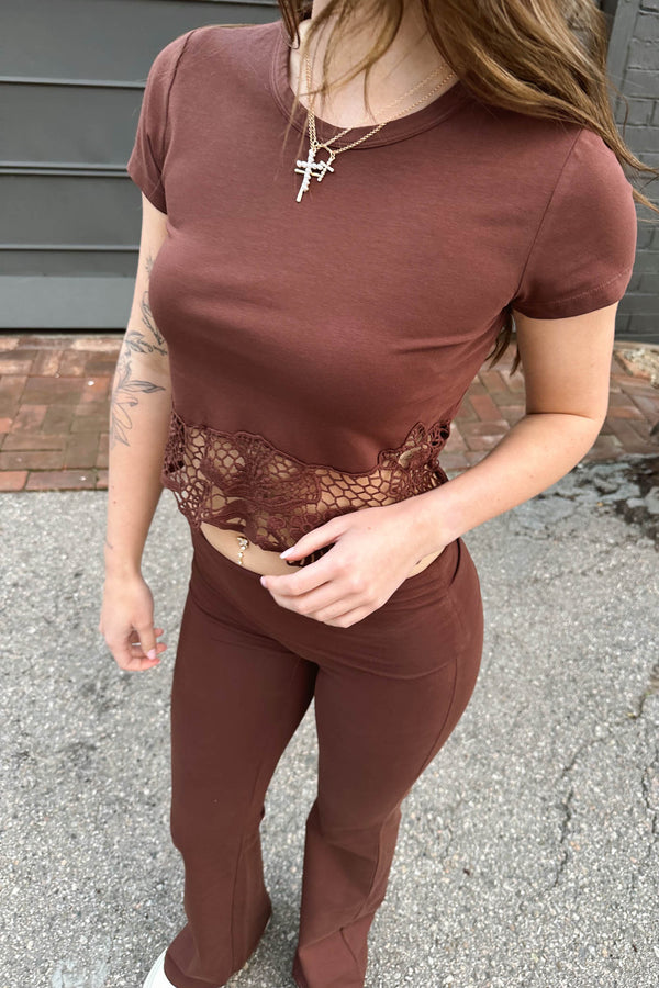 Person wearing a brown outfit with lace detailing outdoors.