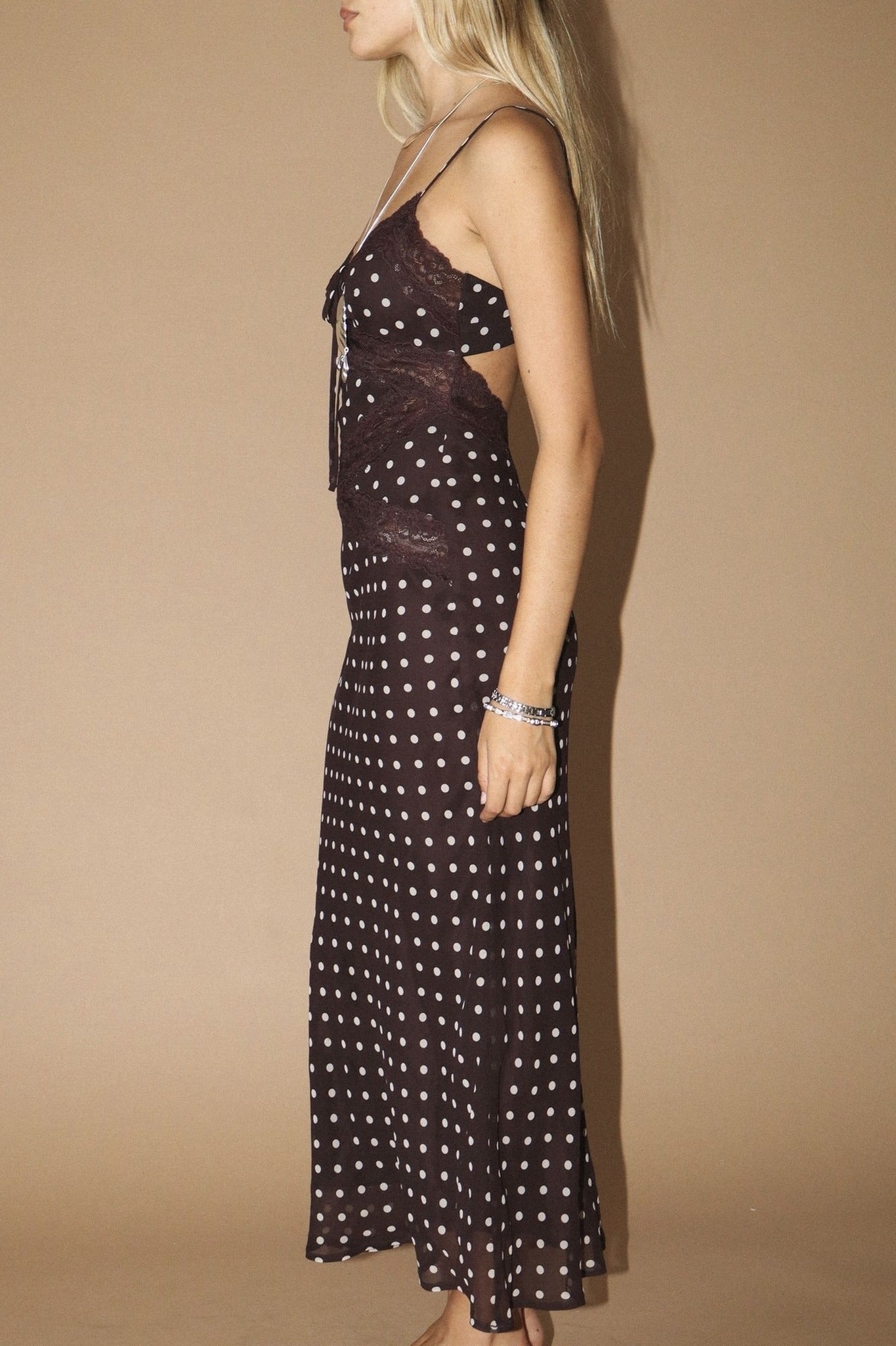 Woman wearing a polka dot dress with cut-out design on a beige background