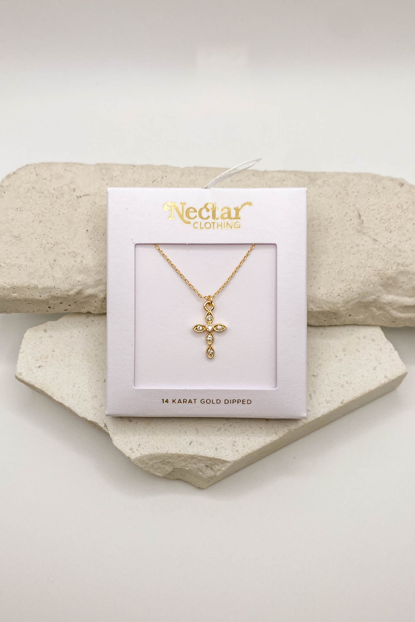Gold necklace on a Nectar Clothing card with a stone background