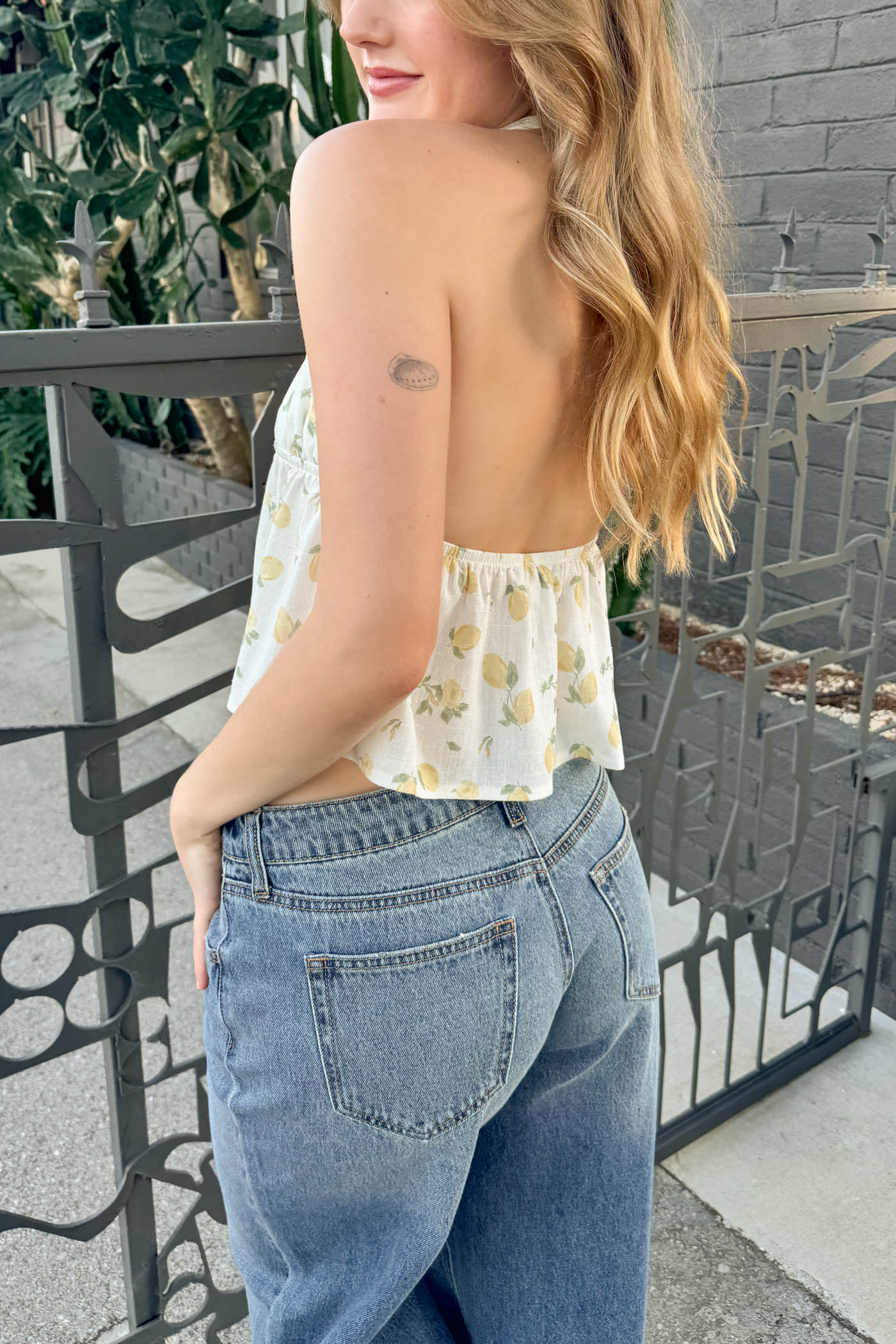 Woman wearing a floral top and blue jeans standing outdoors.