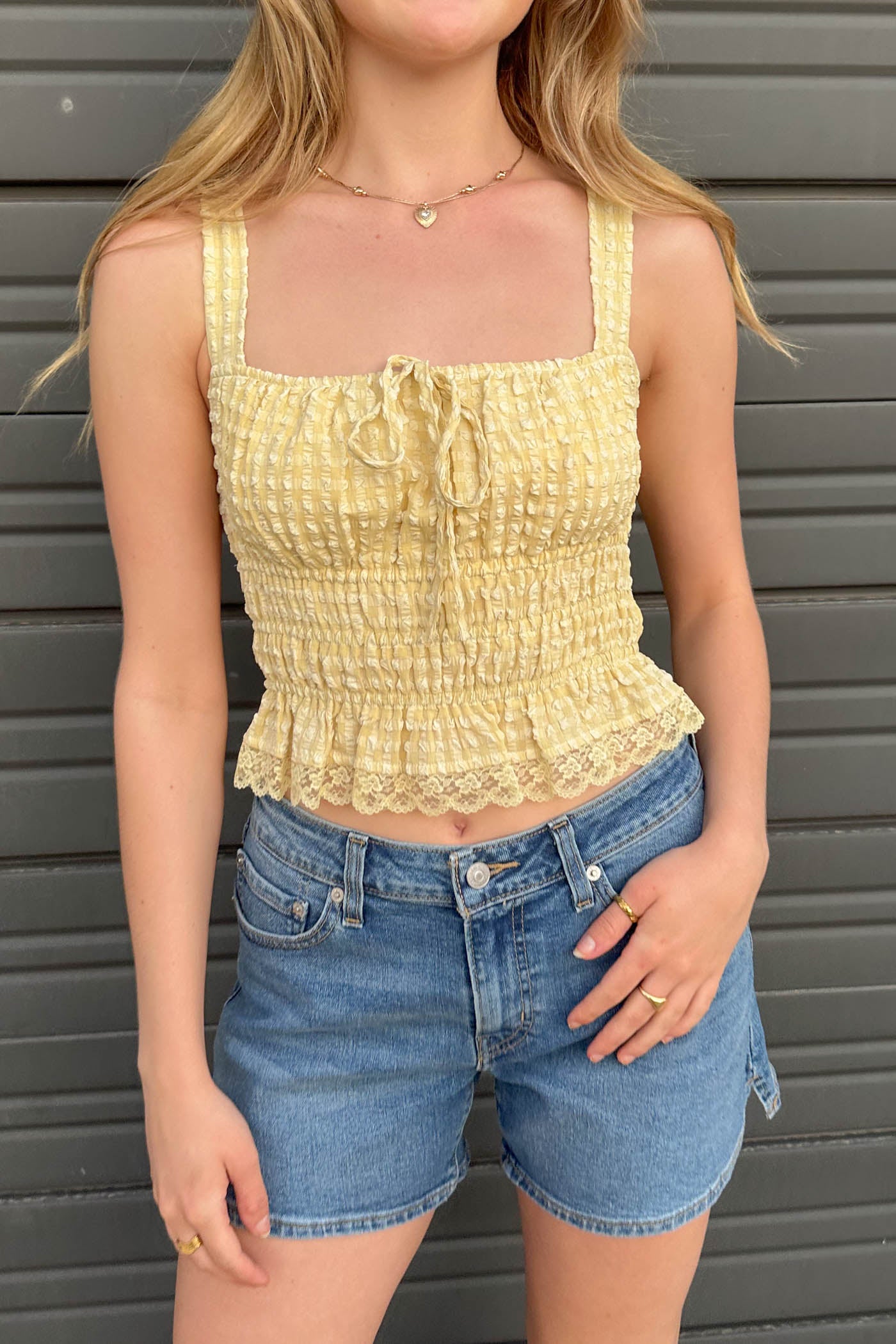 Person wearing a yellow top and blue shorts against a gray background