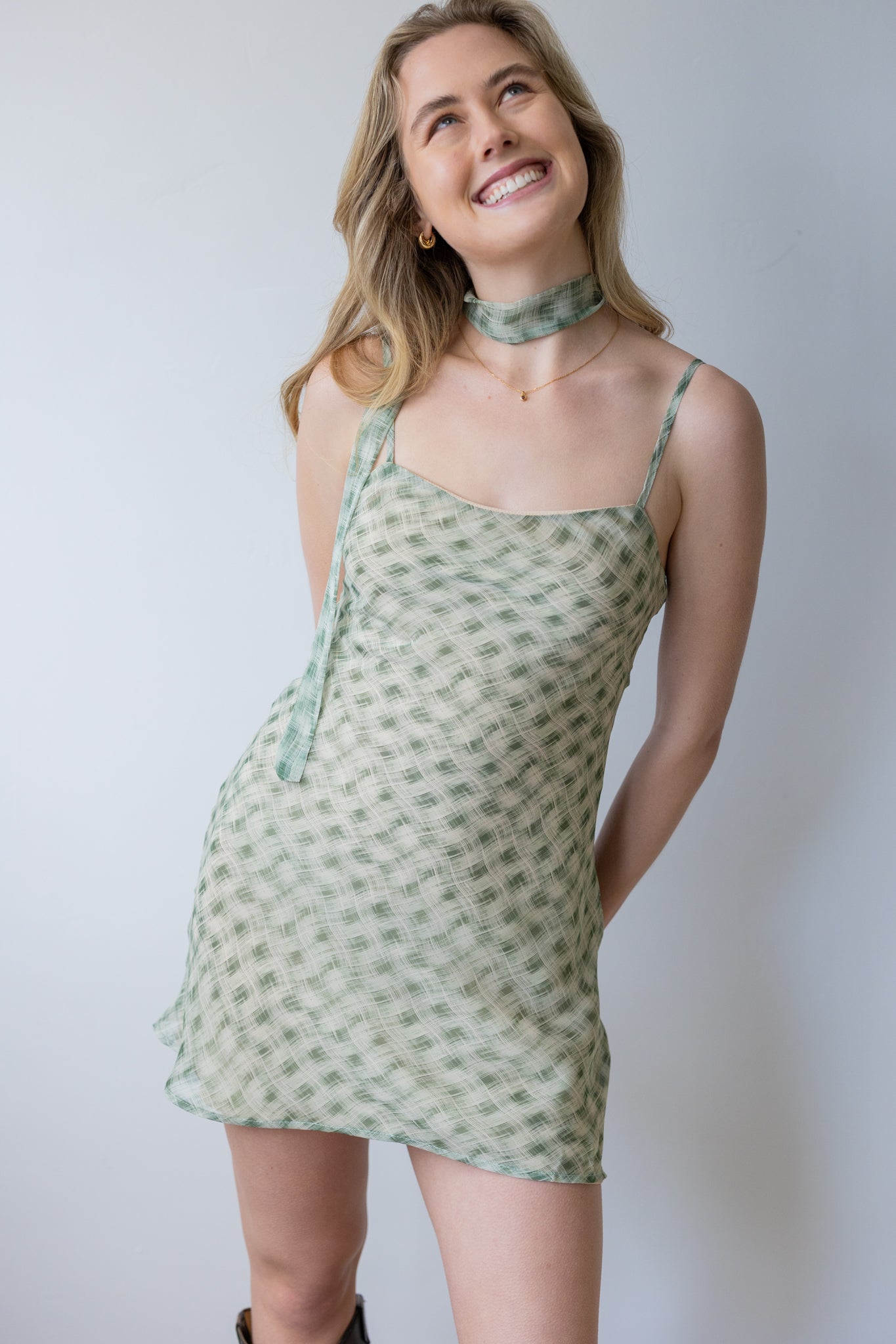 Woman wearing a green patterned dress against a plain background