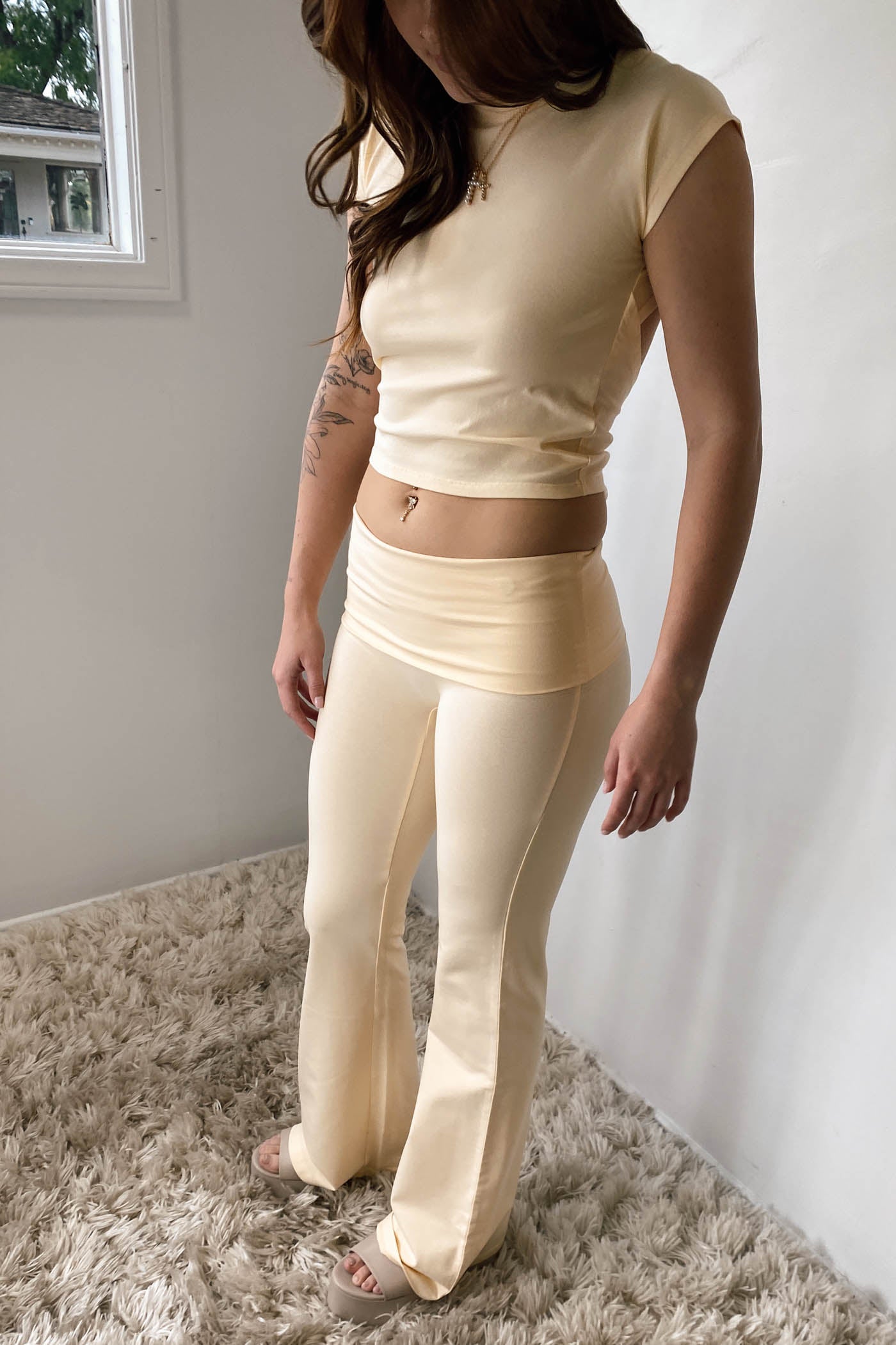 Woman wearing a beige outfit standing in a room with a neutral background