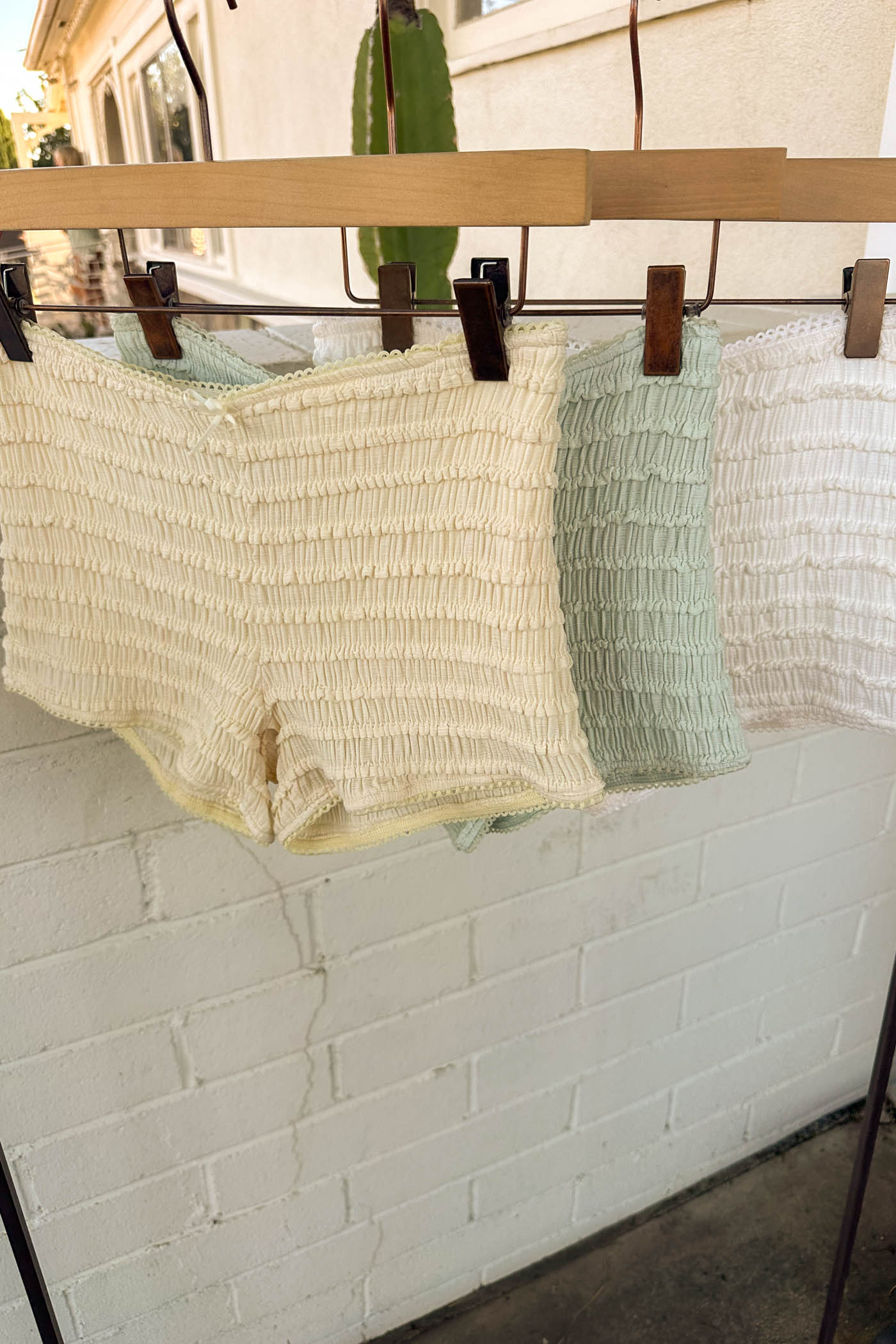 Two pairs of underwear hanging on a clothesline against a white brick wall.