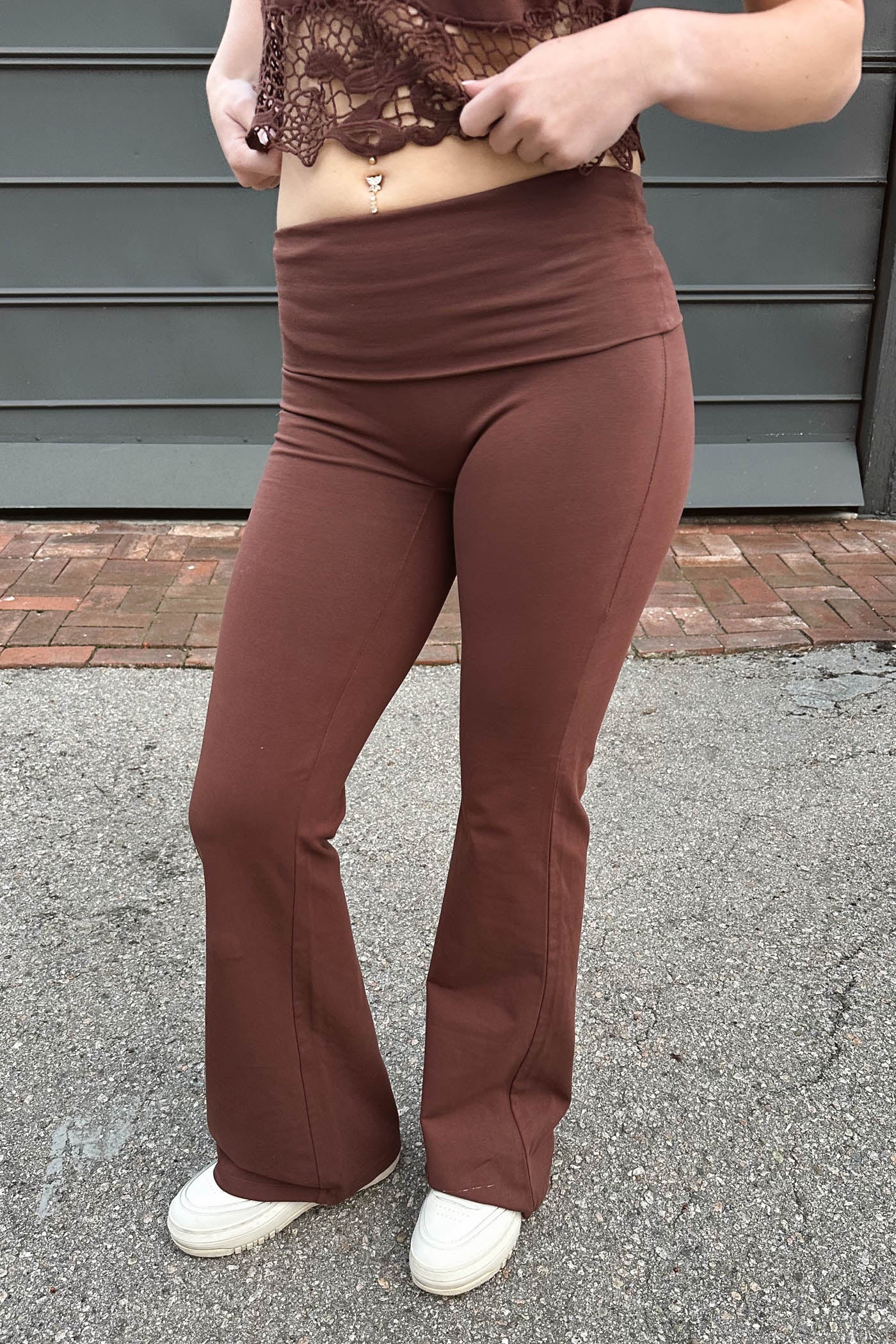Person wearing brown flared pants and a lace top outdoors.