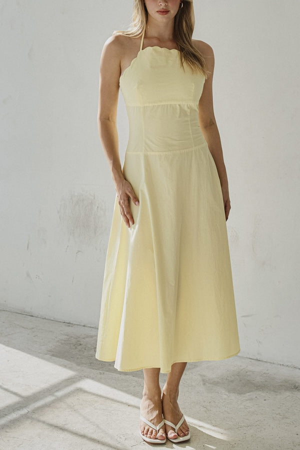 Woman wearing a light yellow dress against a plain background