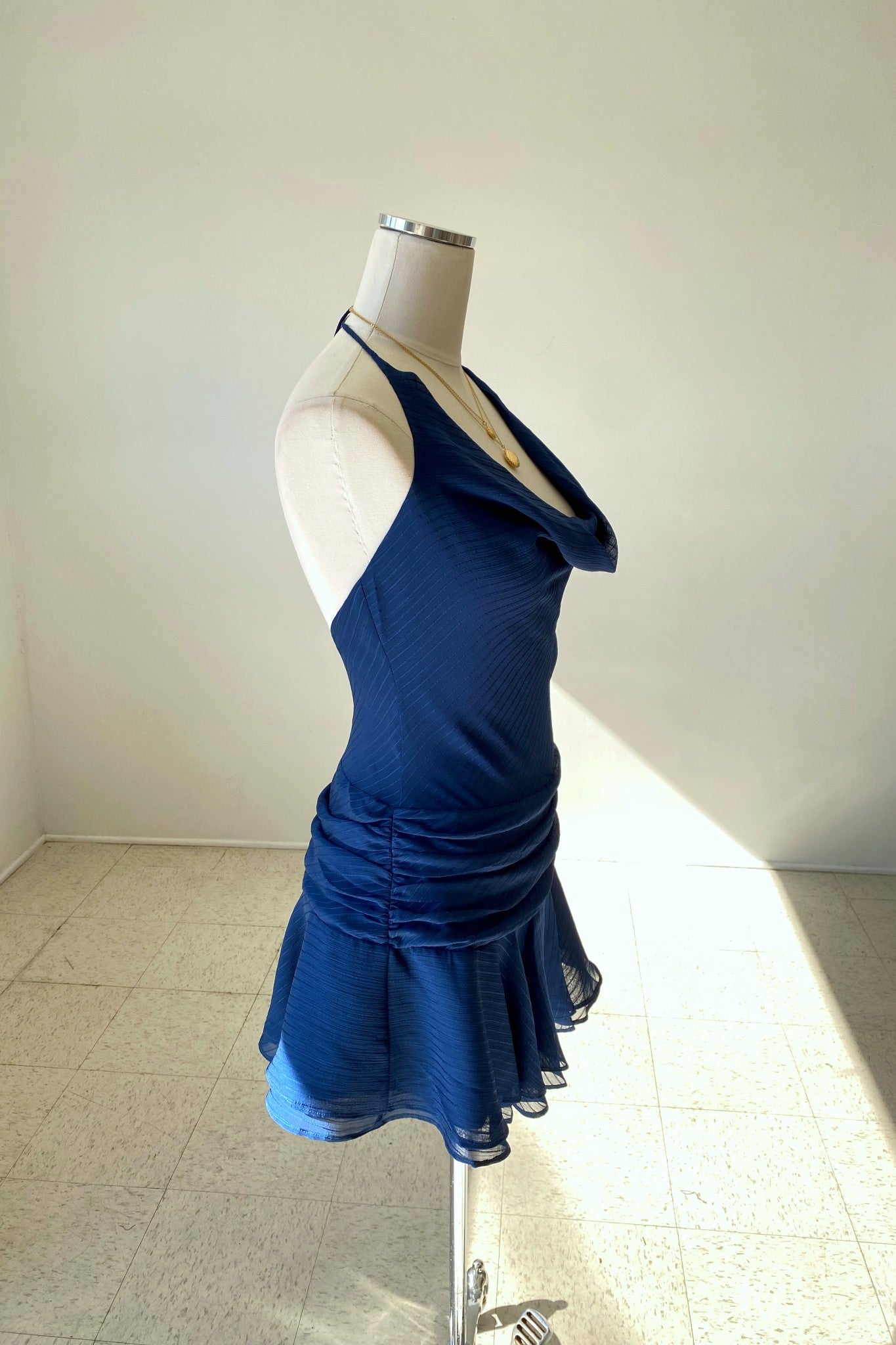 Blue dress on a mannequin against a plain background