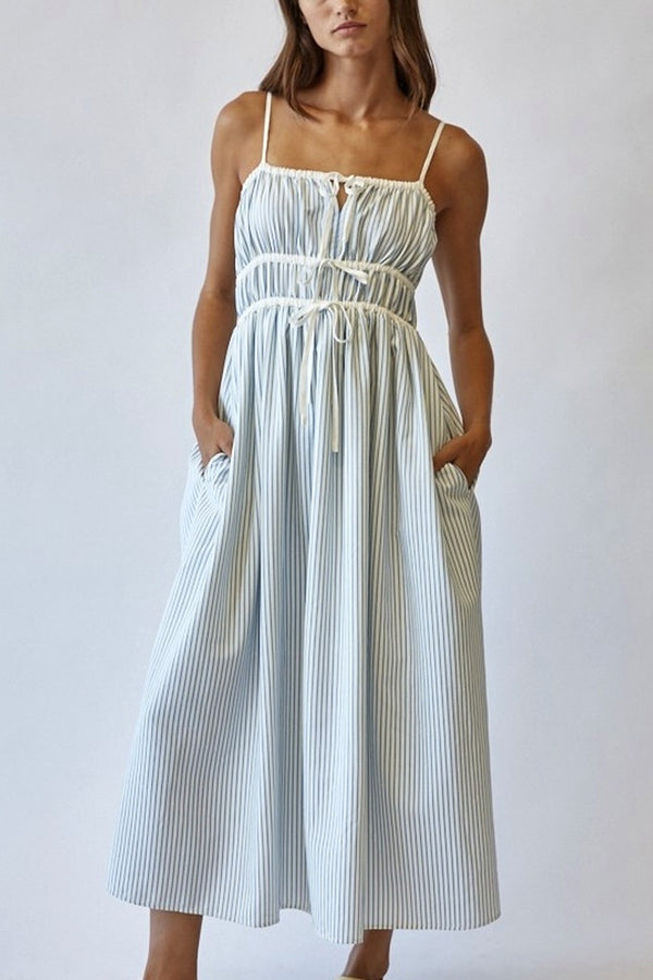 Woman wearing a white and blue striped dress against a plain background