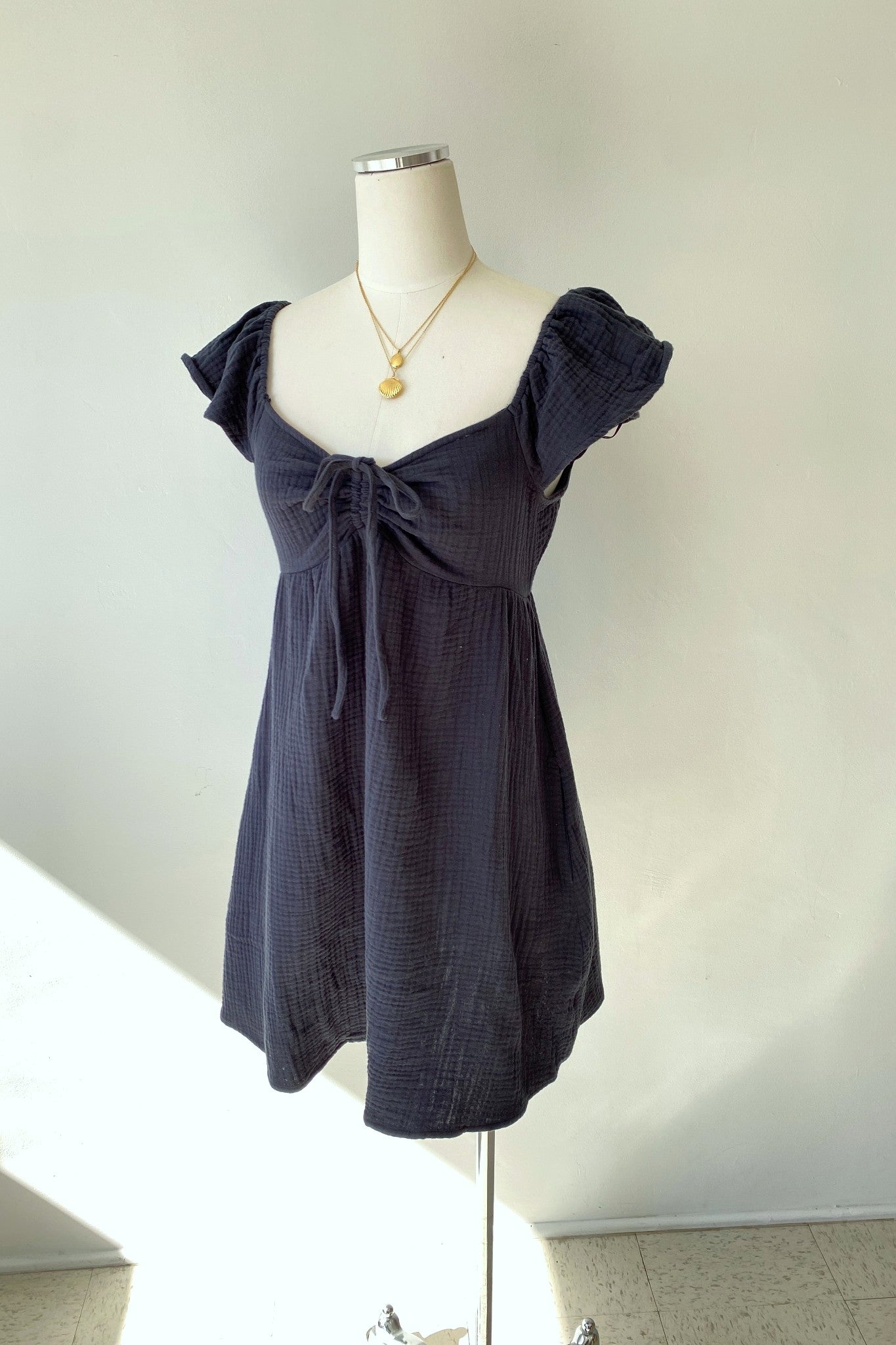 Navy blue dress on a mannequin against a white wall