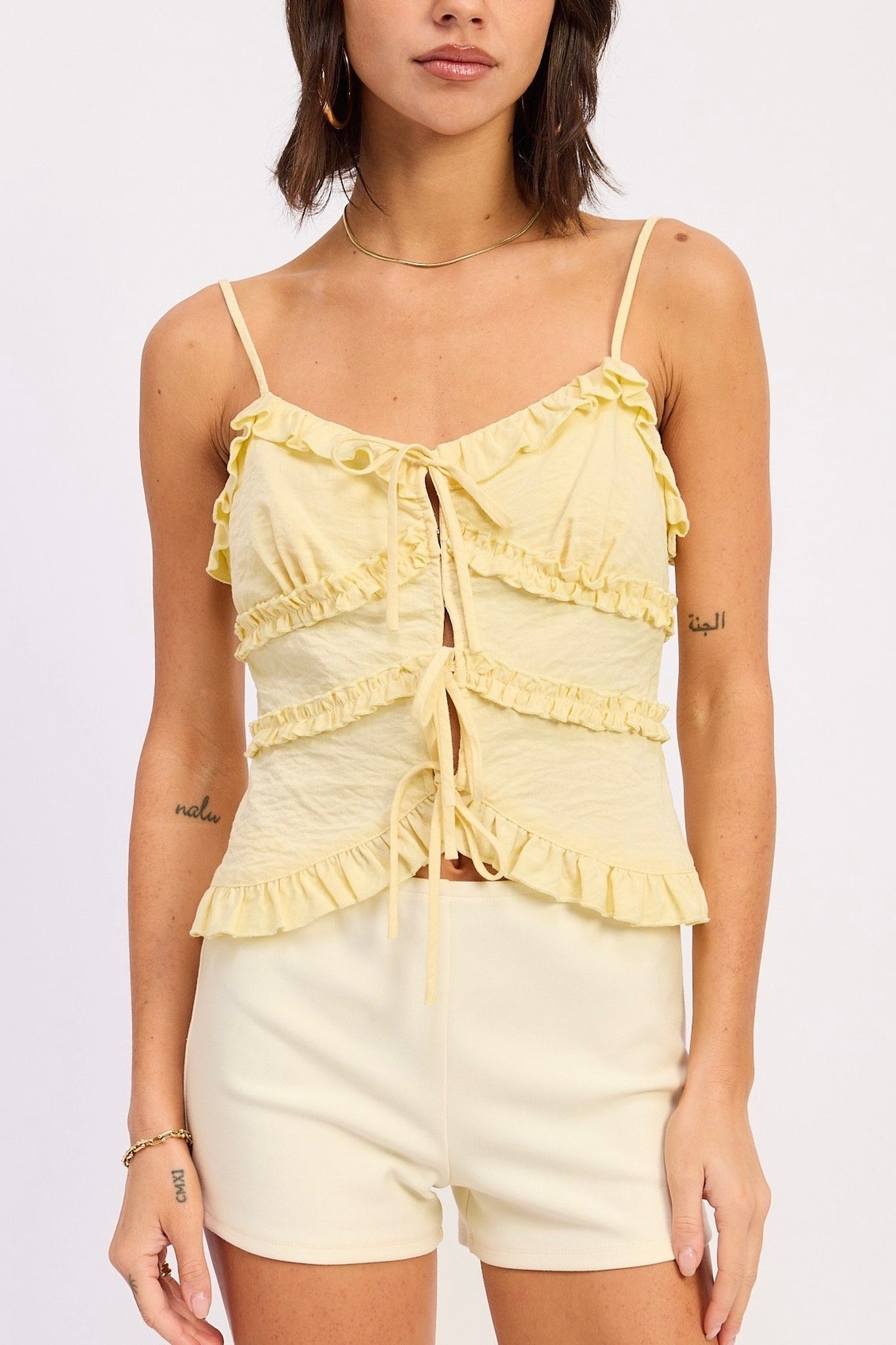 Woman wearing a yellow ruffled top and shorts on a white background