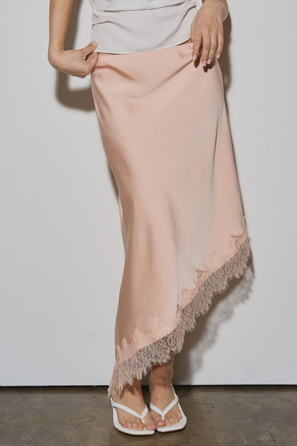 Person wearing a light pink satin skirt with lace trim on a plain background