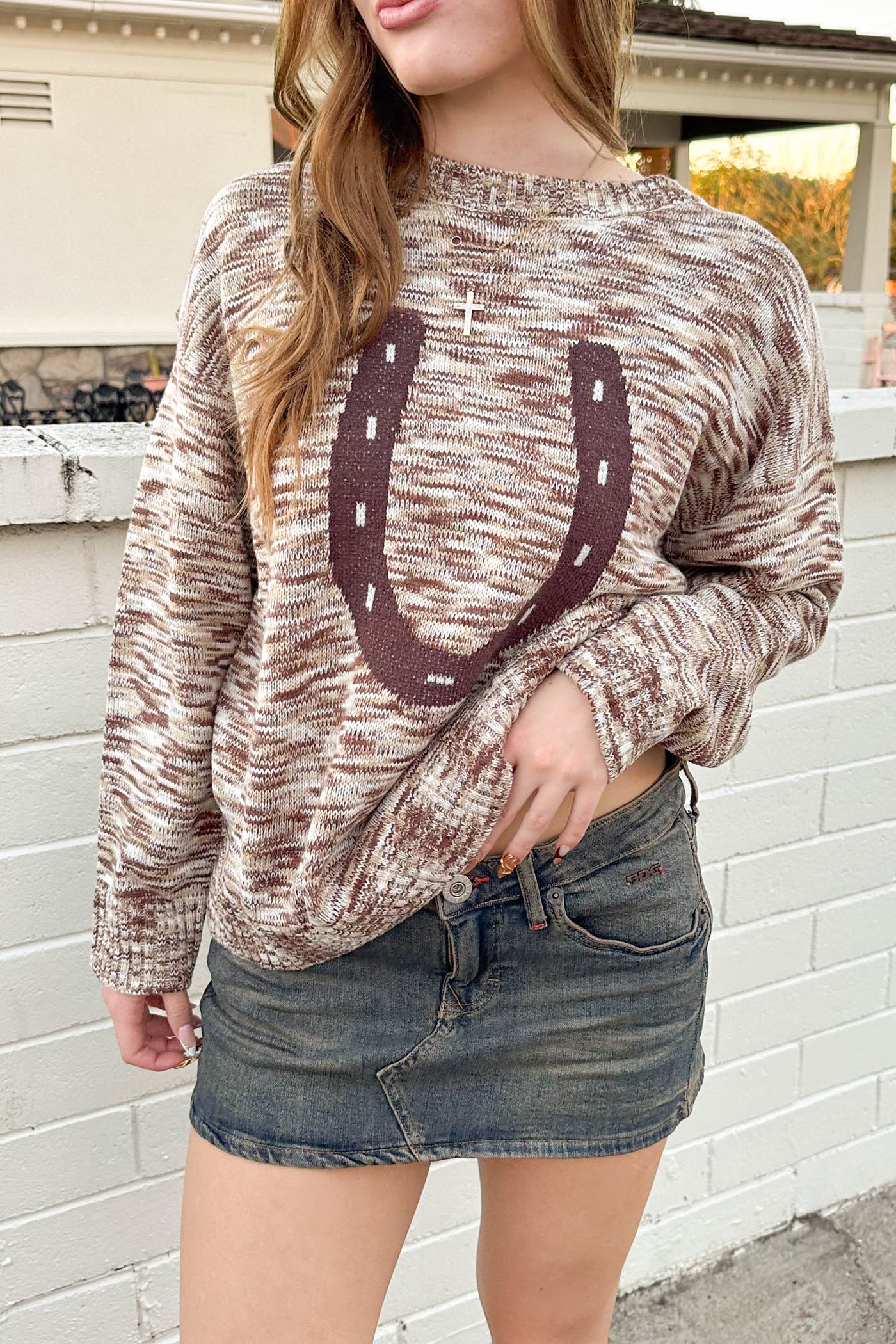 Person wearing a patterned sweater with a horse shoe design outdoors.