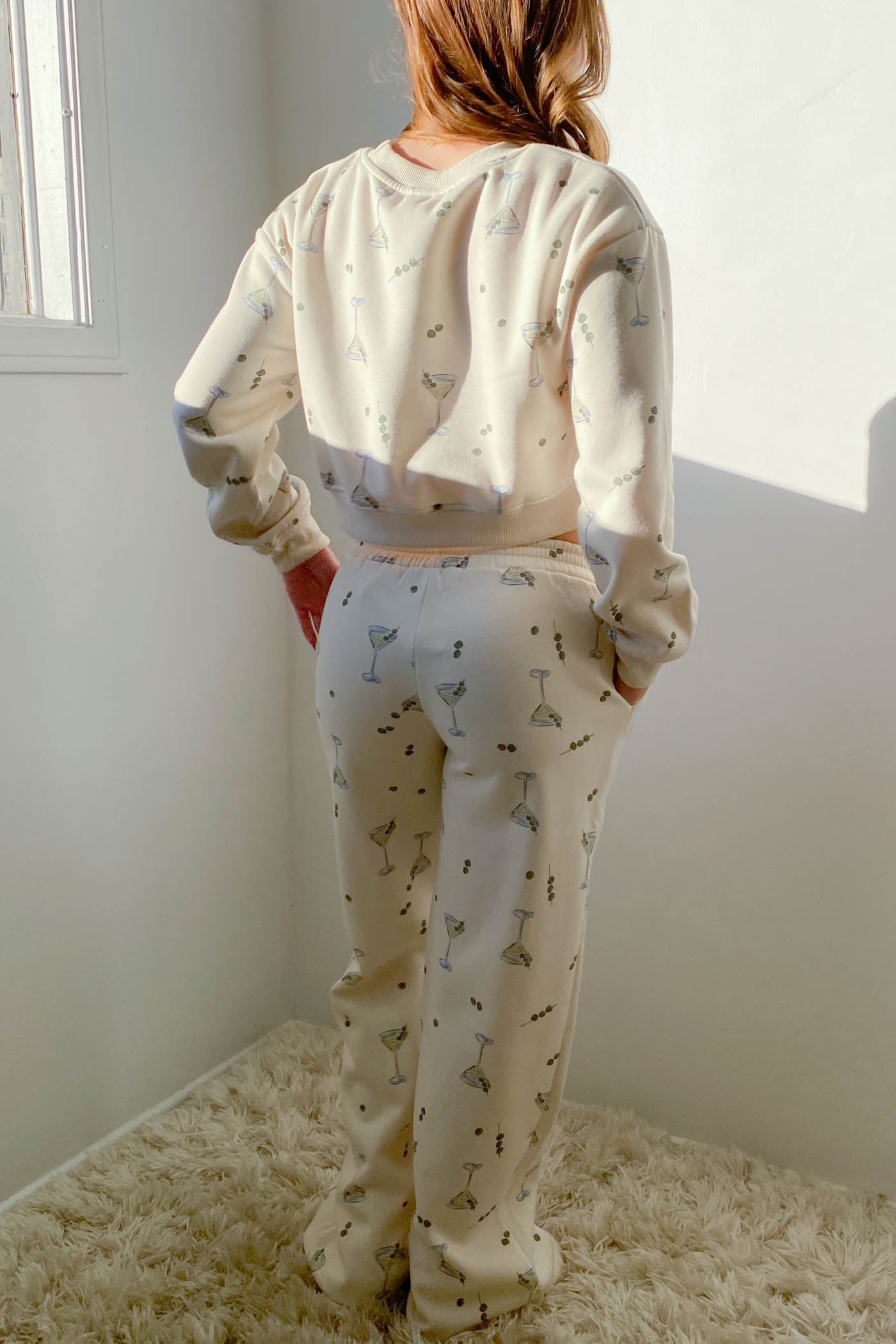 Person wearing a cream-colored pajama set with small patterns in a minimal room.